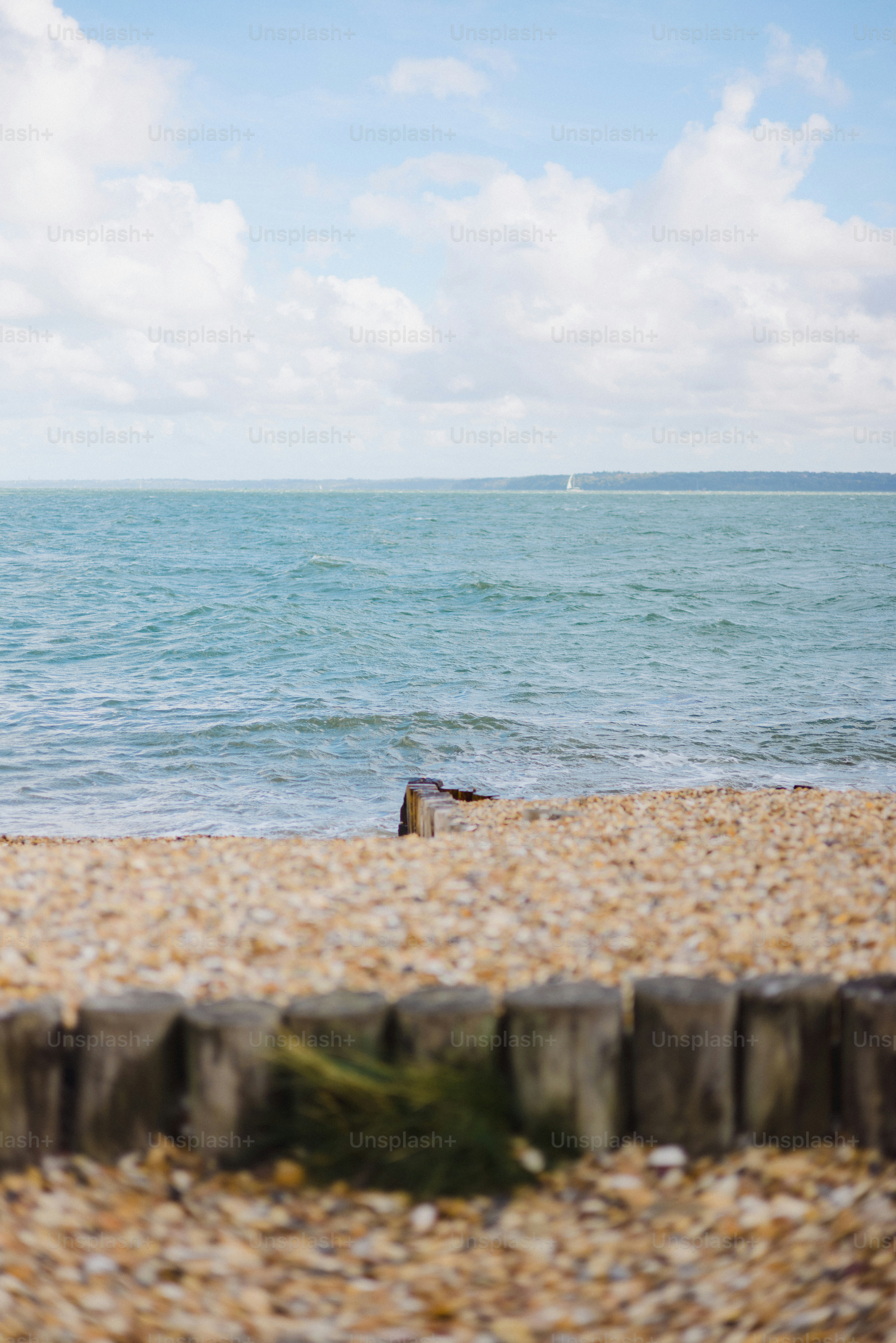 Pebble beach with wooden posts and calm ocean