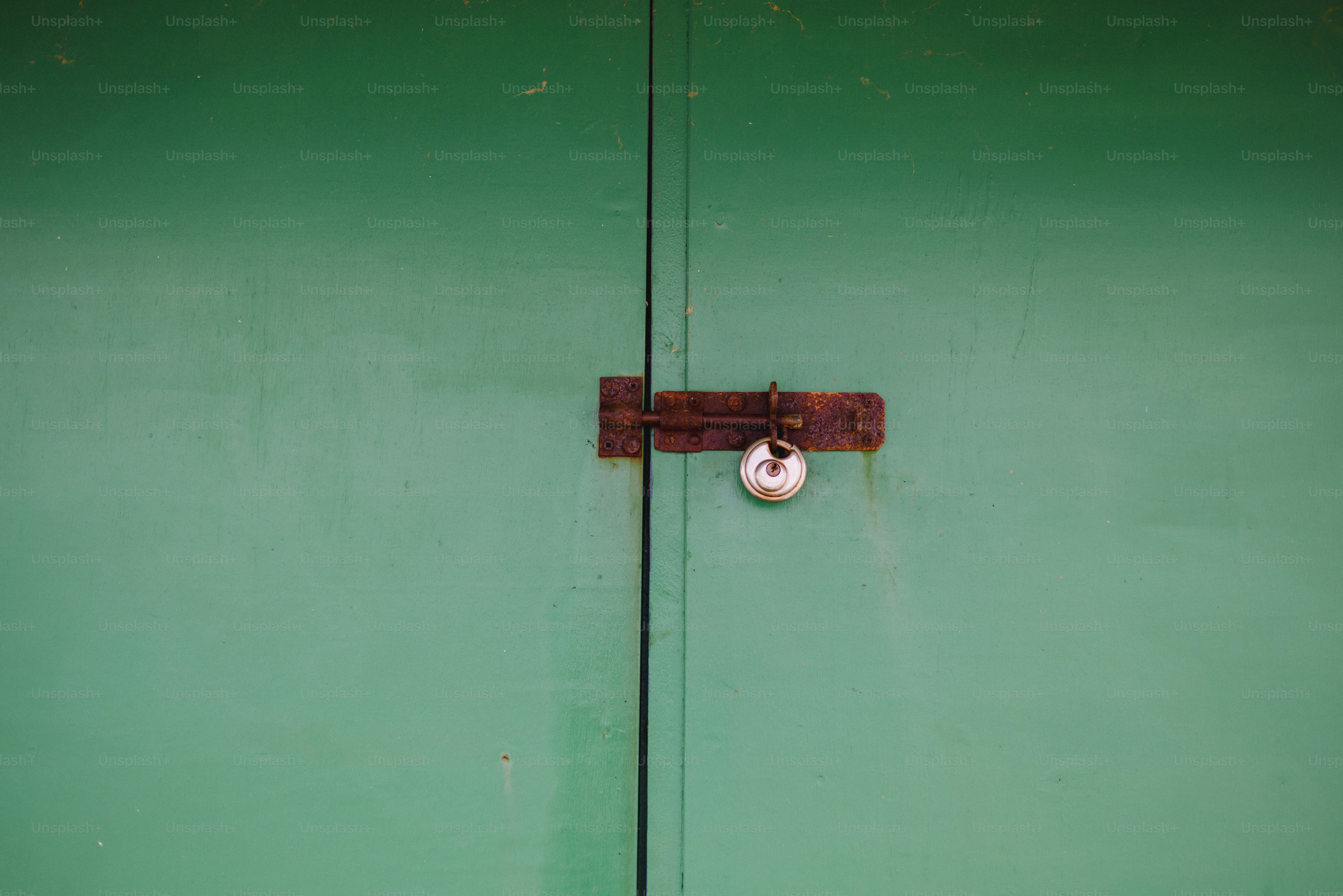 Green doors with a rusty padlock and bolt