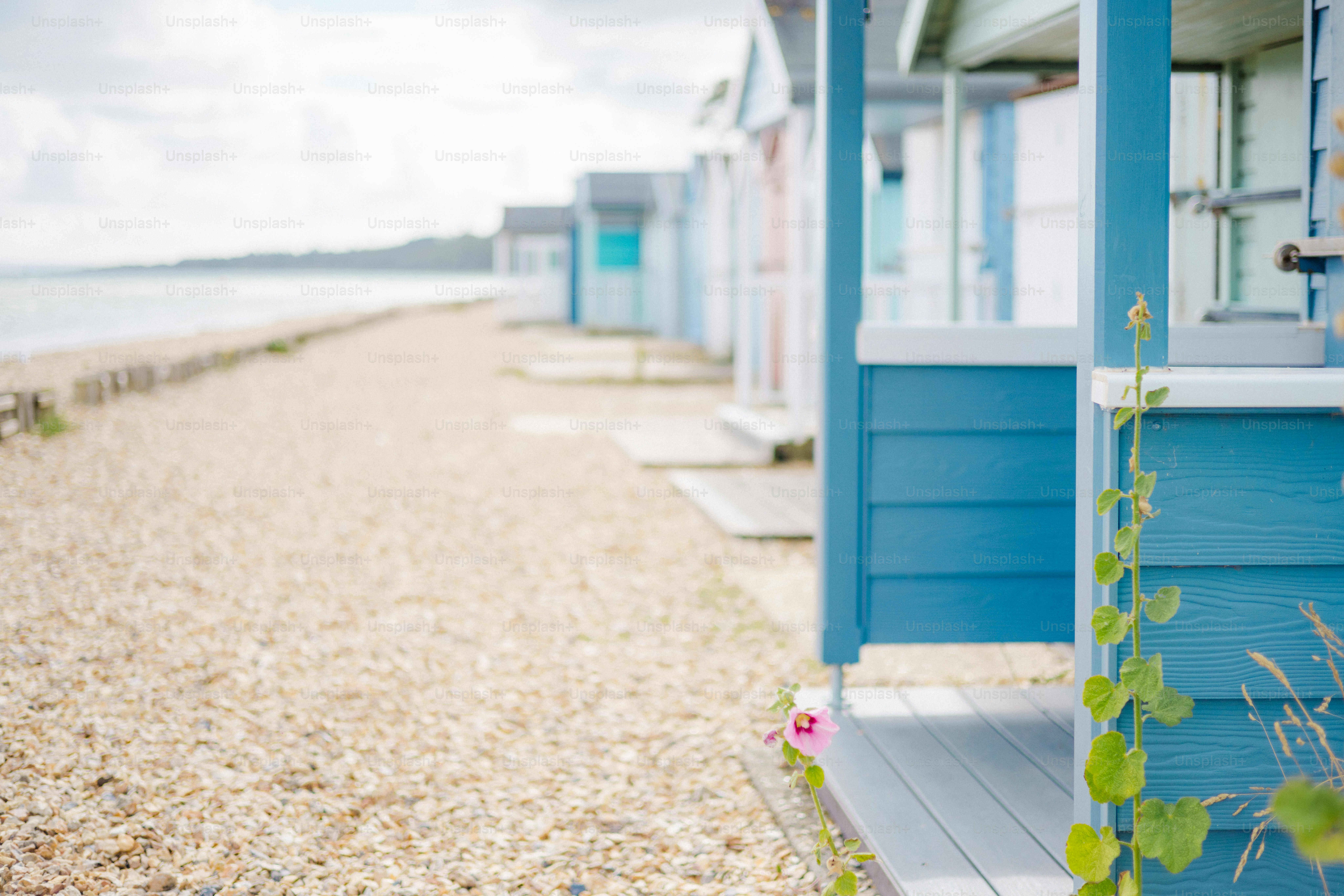 Colorful beach huts line a pebble shore.