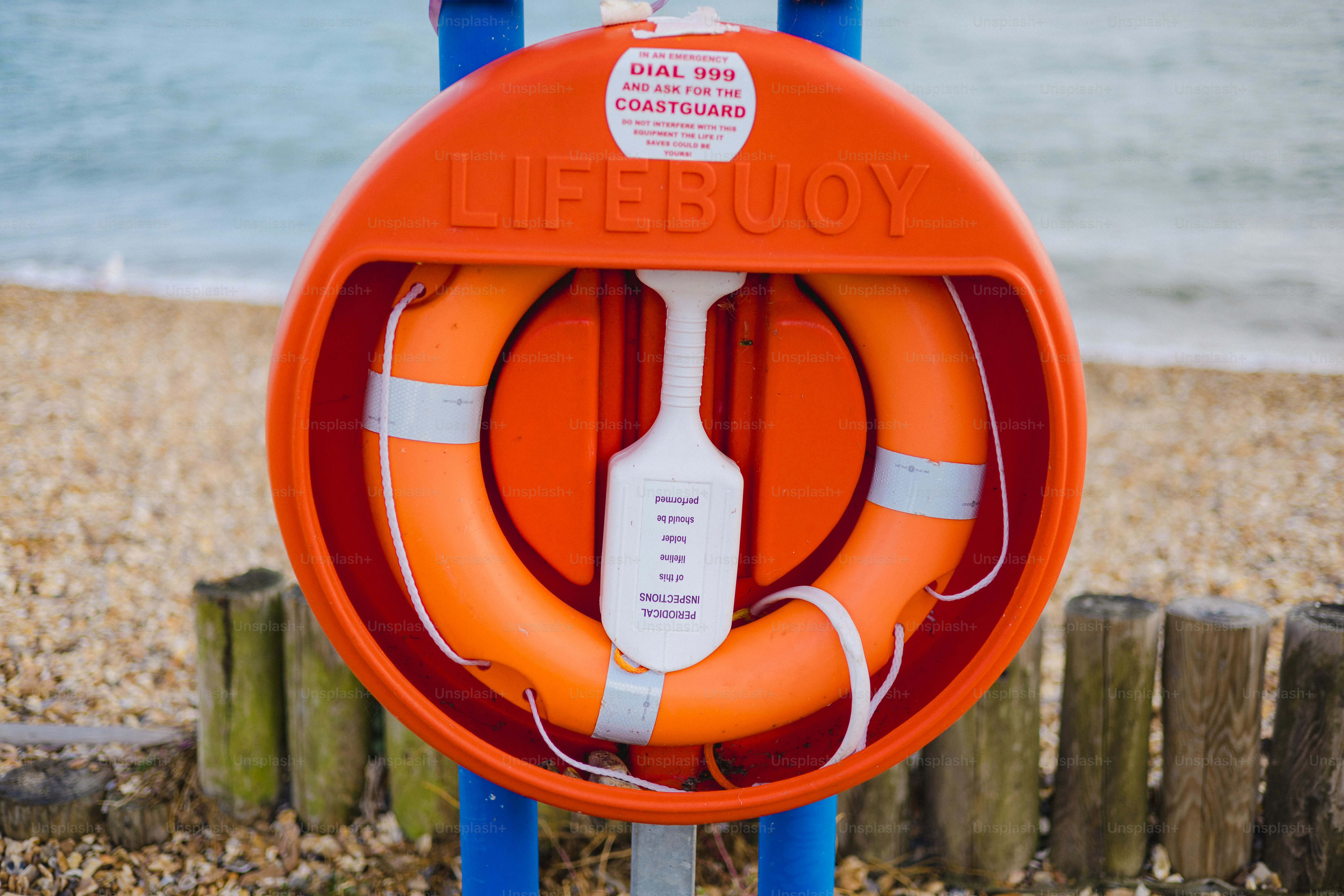 Orange lifebuoy in a red case on a beach