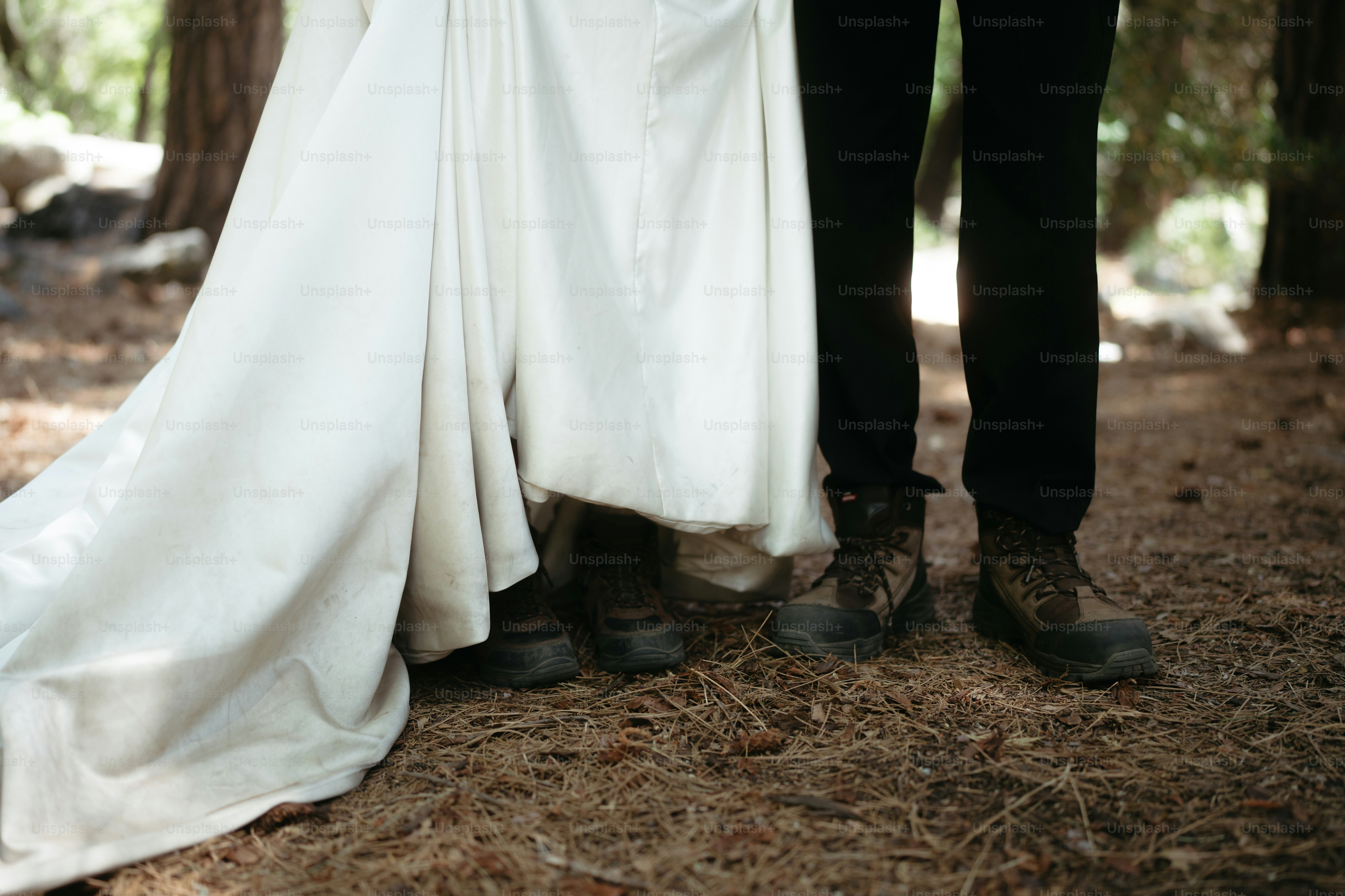 Couple in wedding attire with boots in forest.