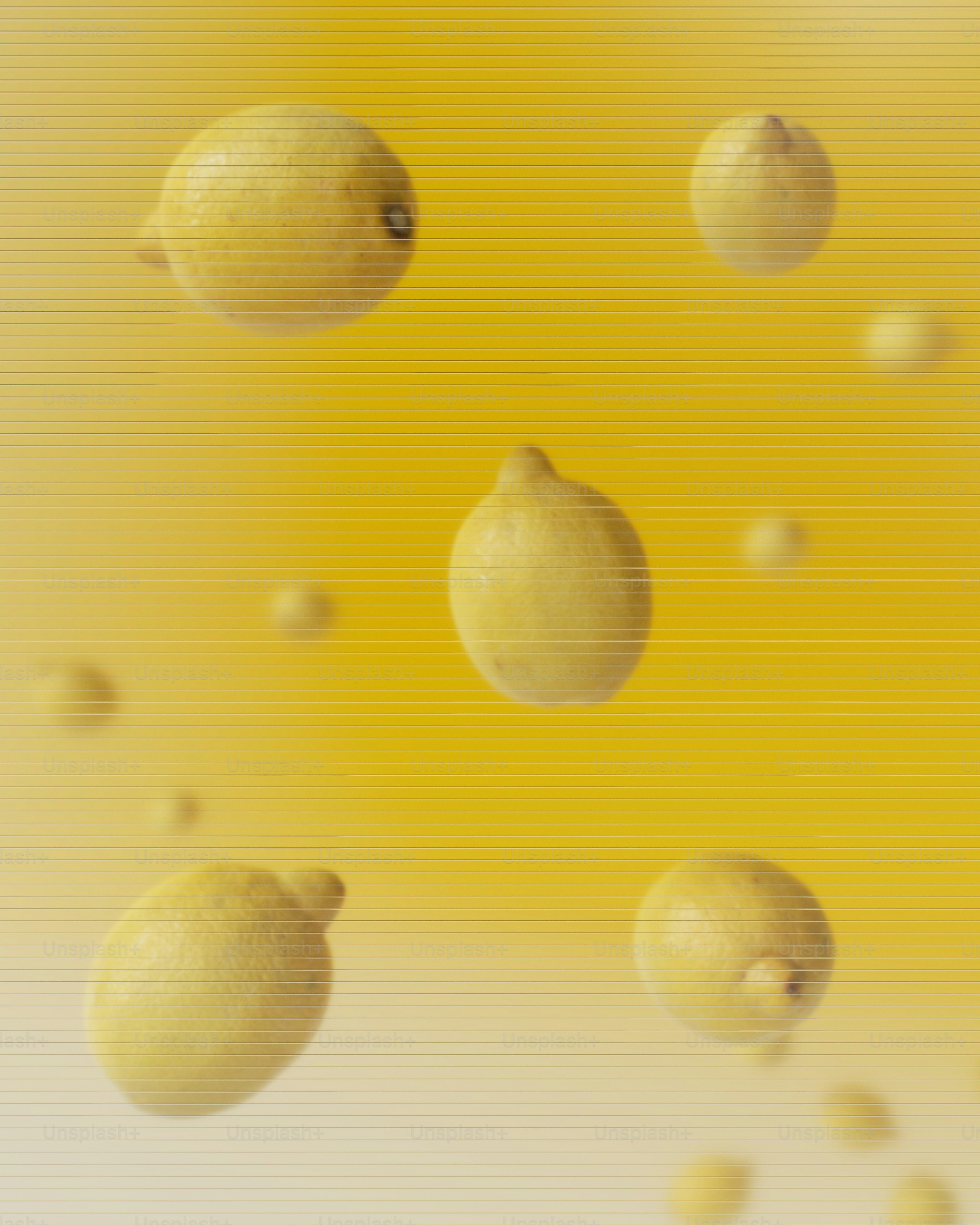 Varios limones suspendidos sobre un fondo amarillo