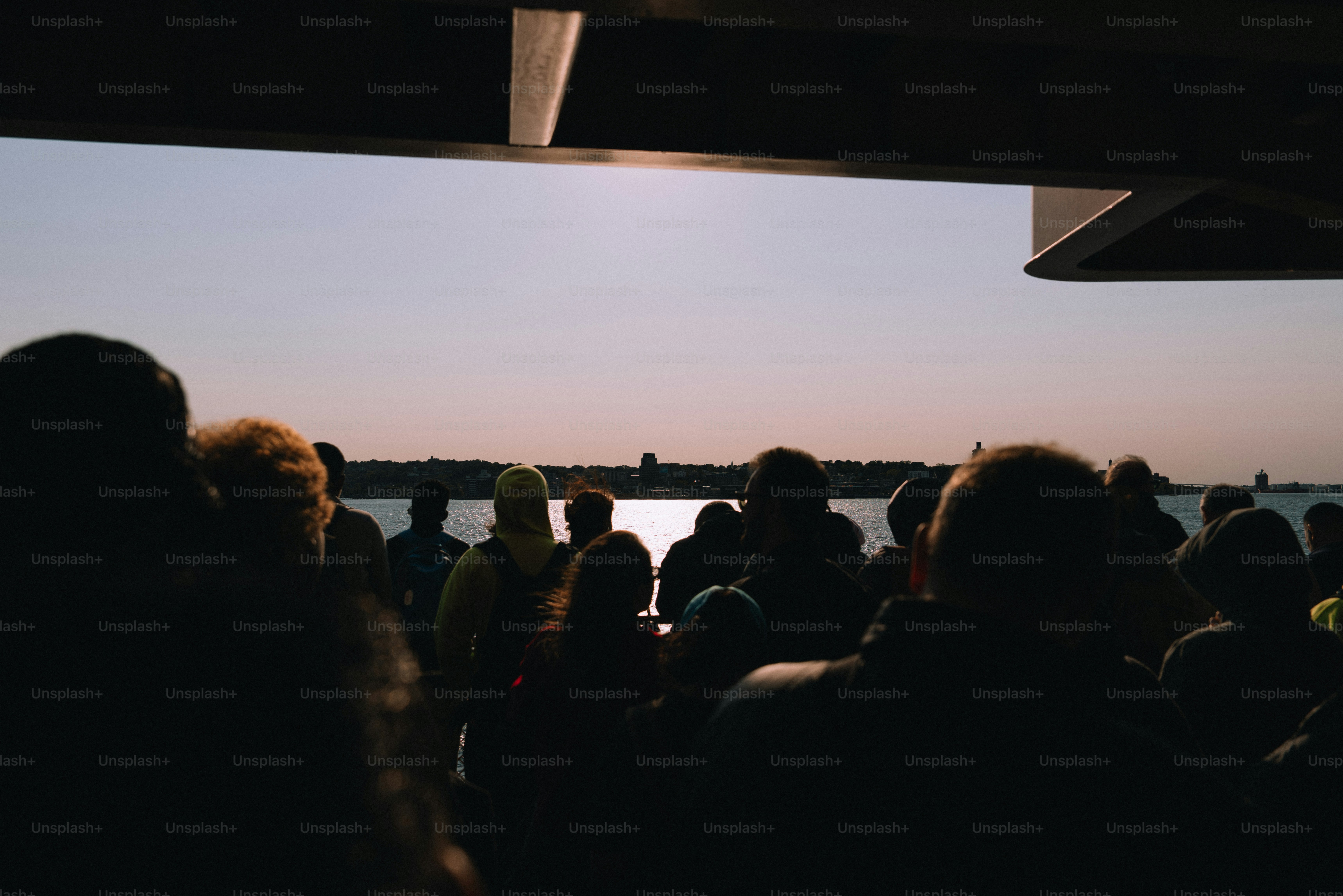 Silhouetted crowd watches sunset over water