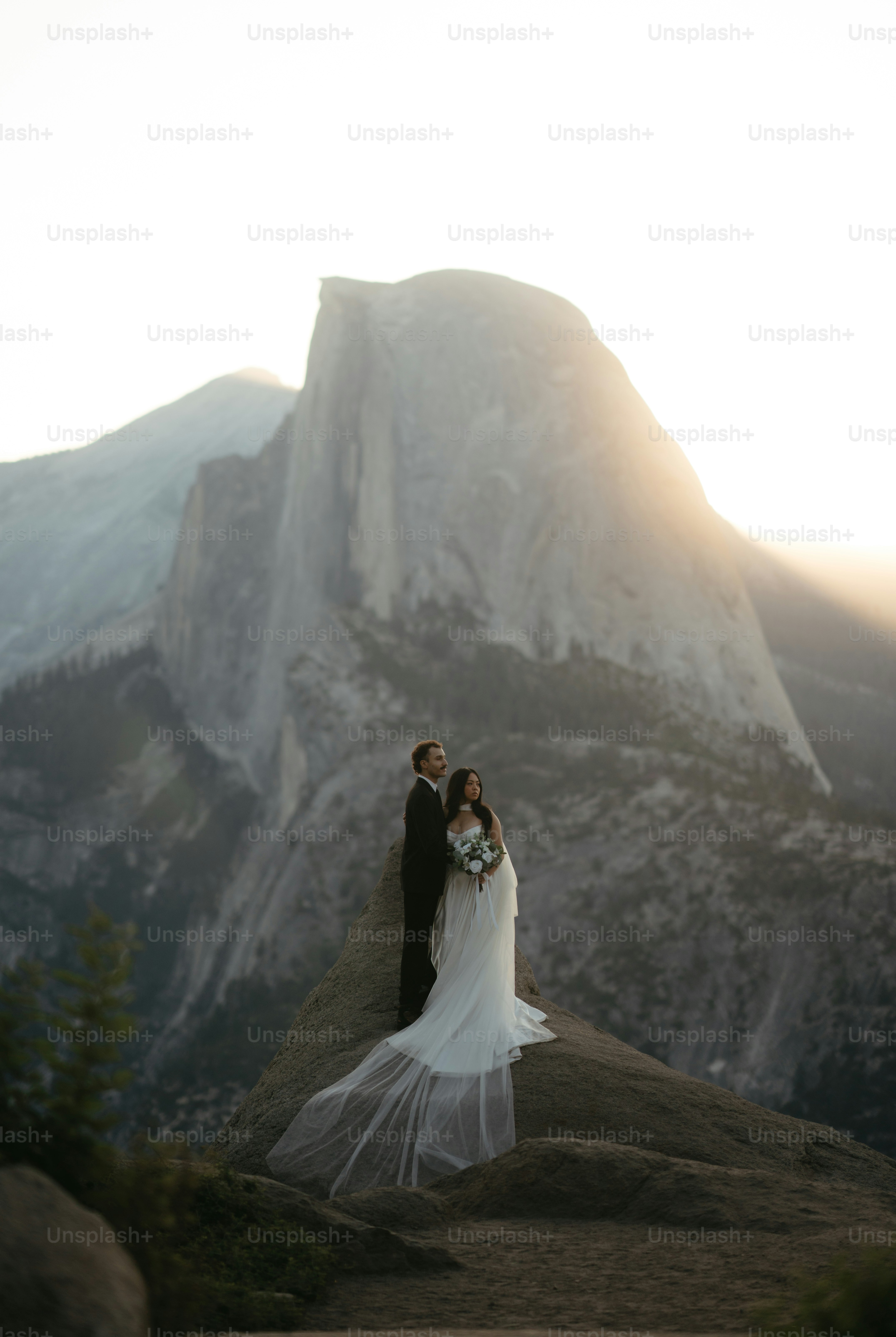 Bride and groom posing on a cliff with half dome.
