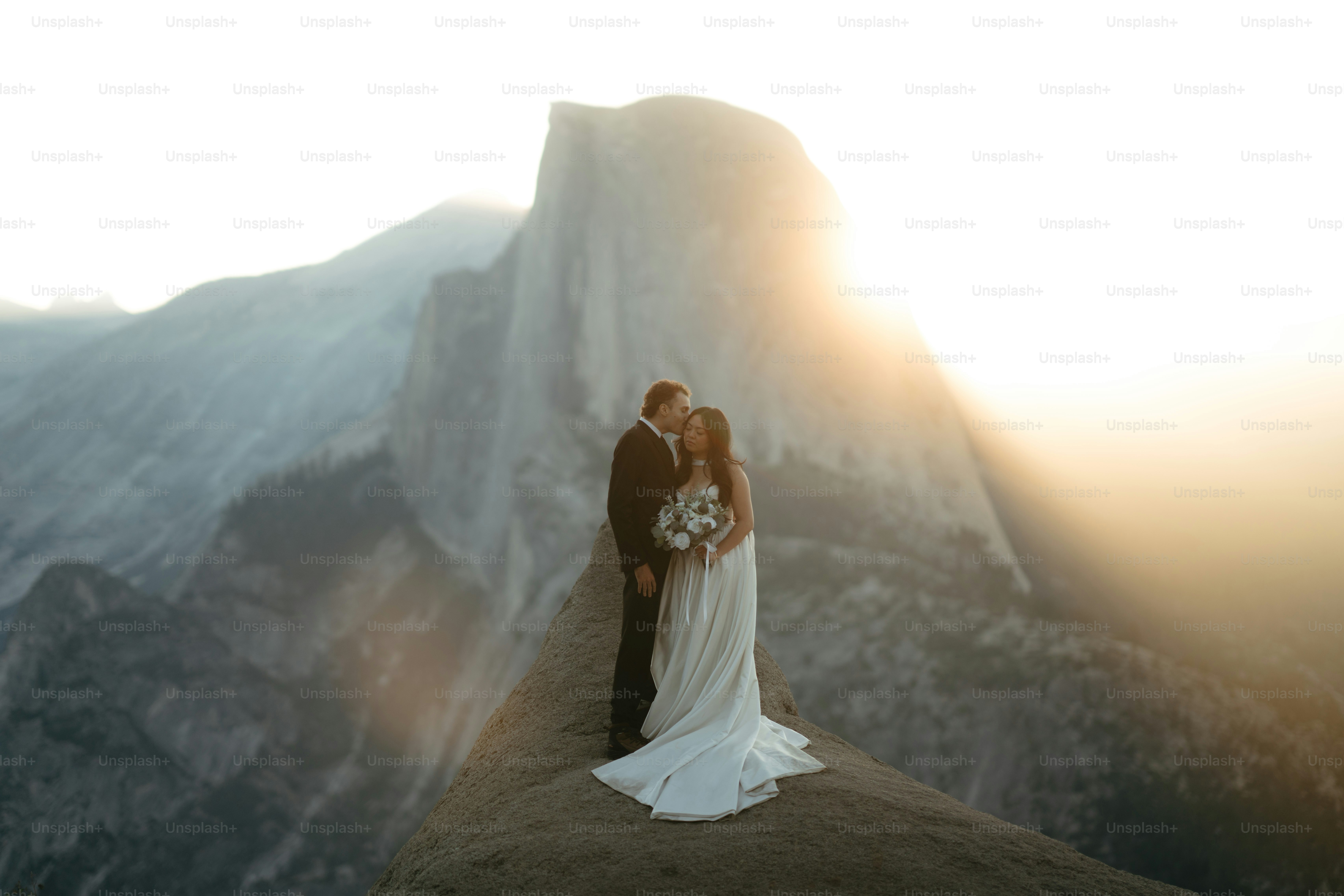 Bride and groom kissing on a mountain at sunset