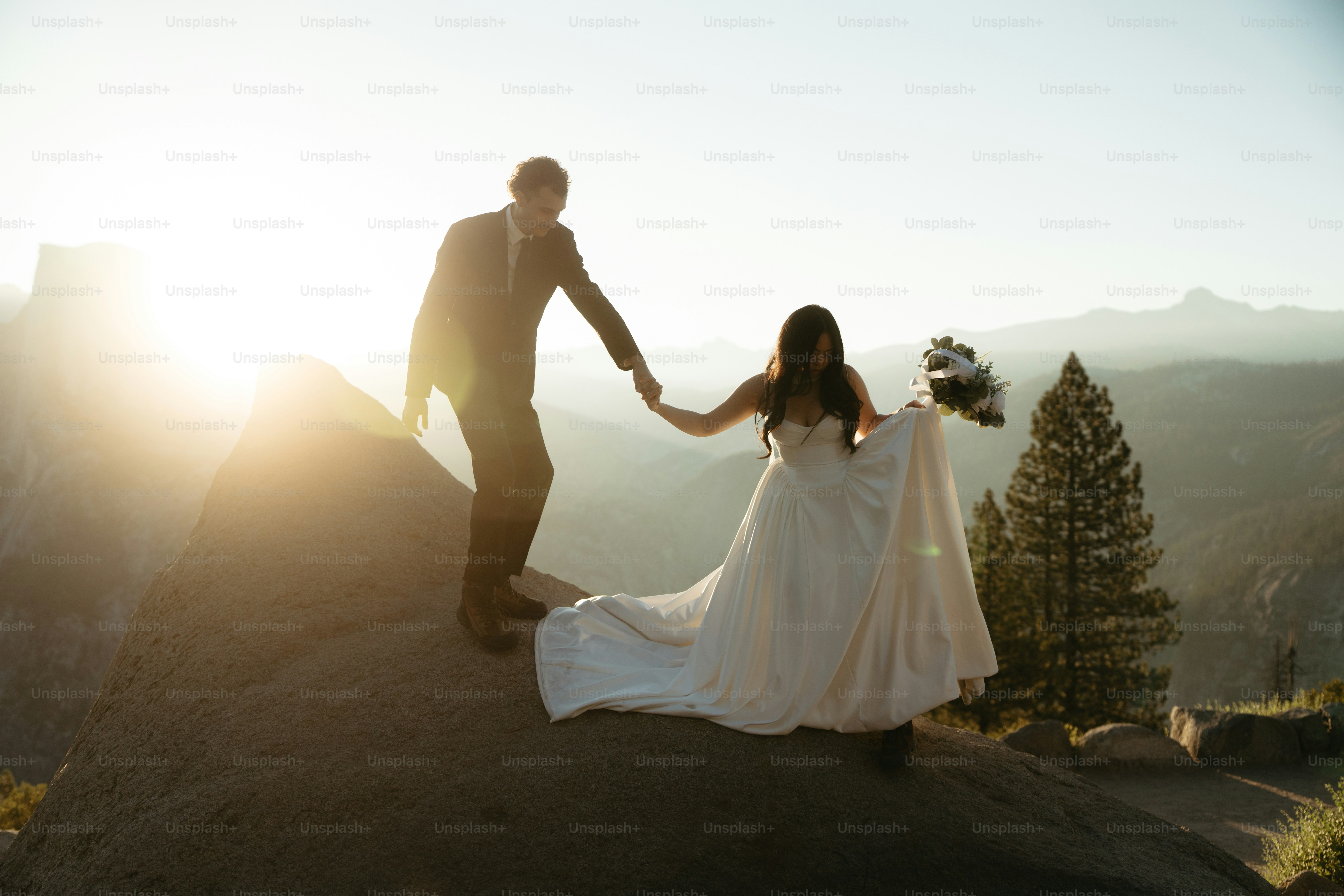 Couple holding hands on rocky mountain at sunset