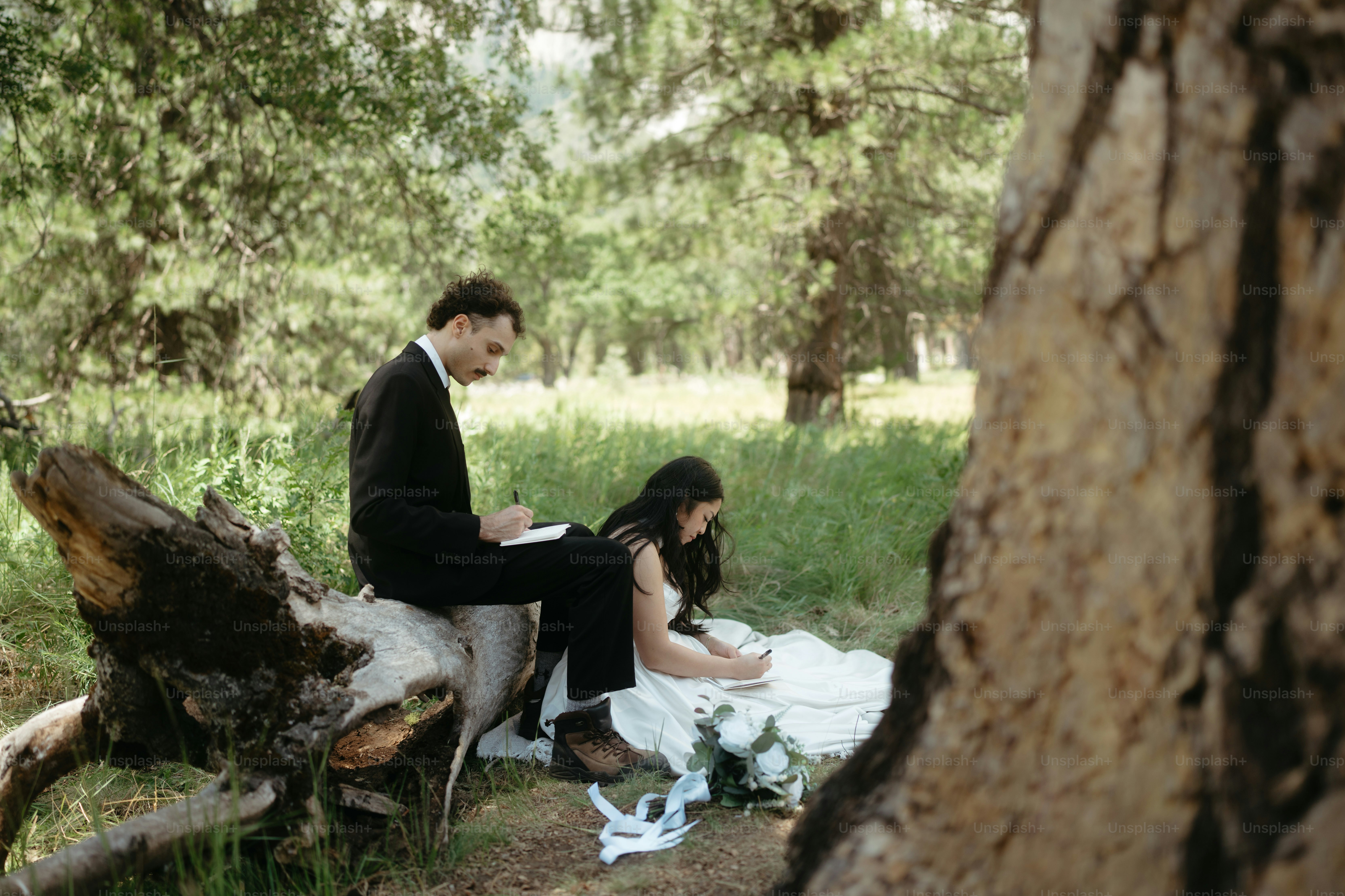Couple writing in a forest with a tree trunk