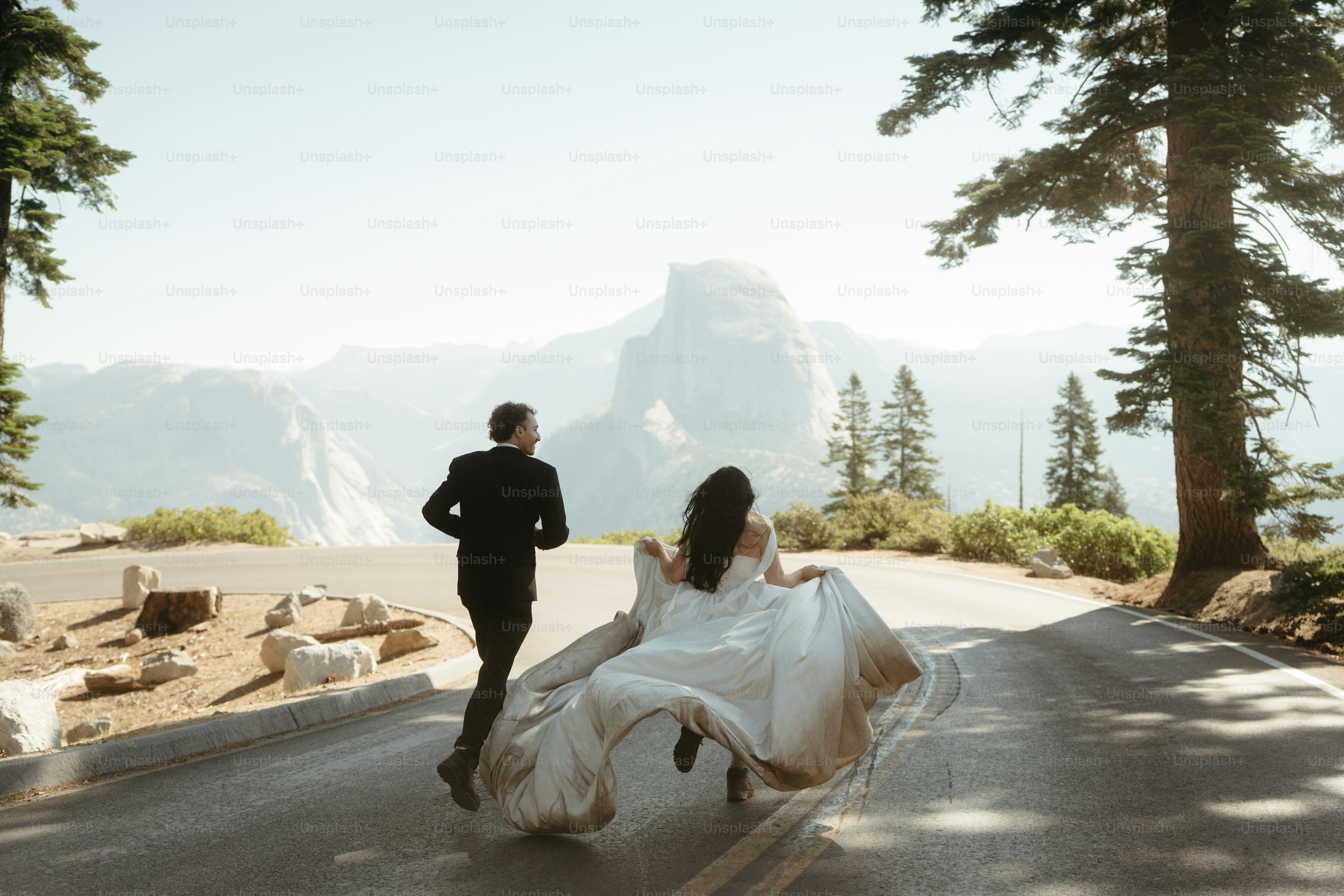 Newlyweds run across road with mountain view