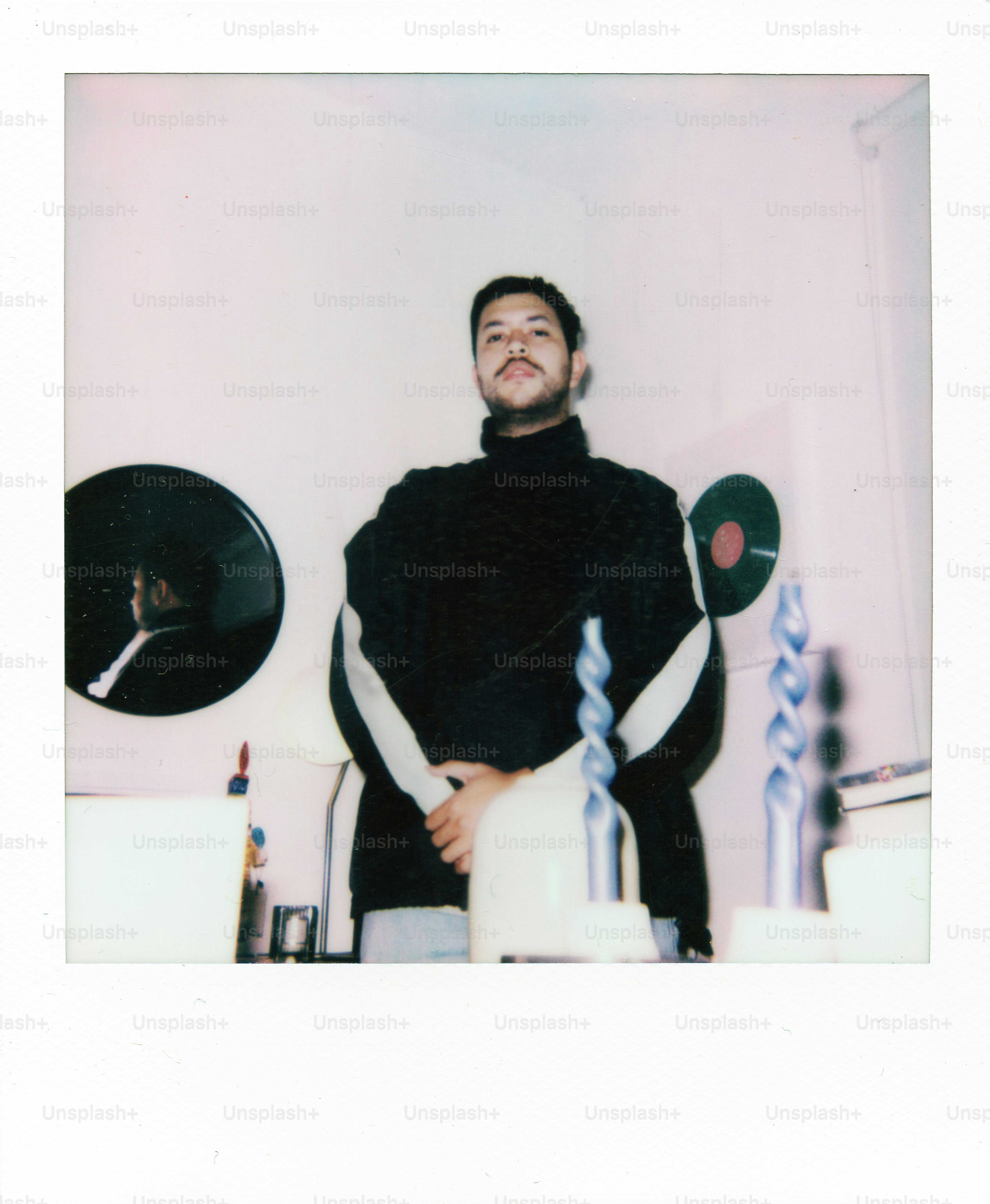 Man in black turtleneck standing indoors with records.