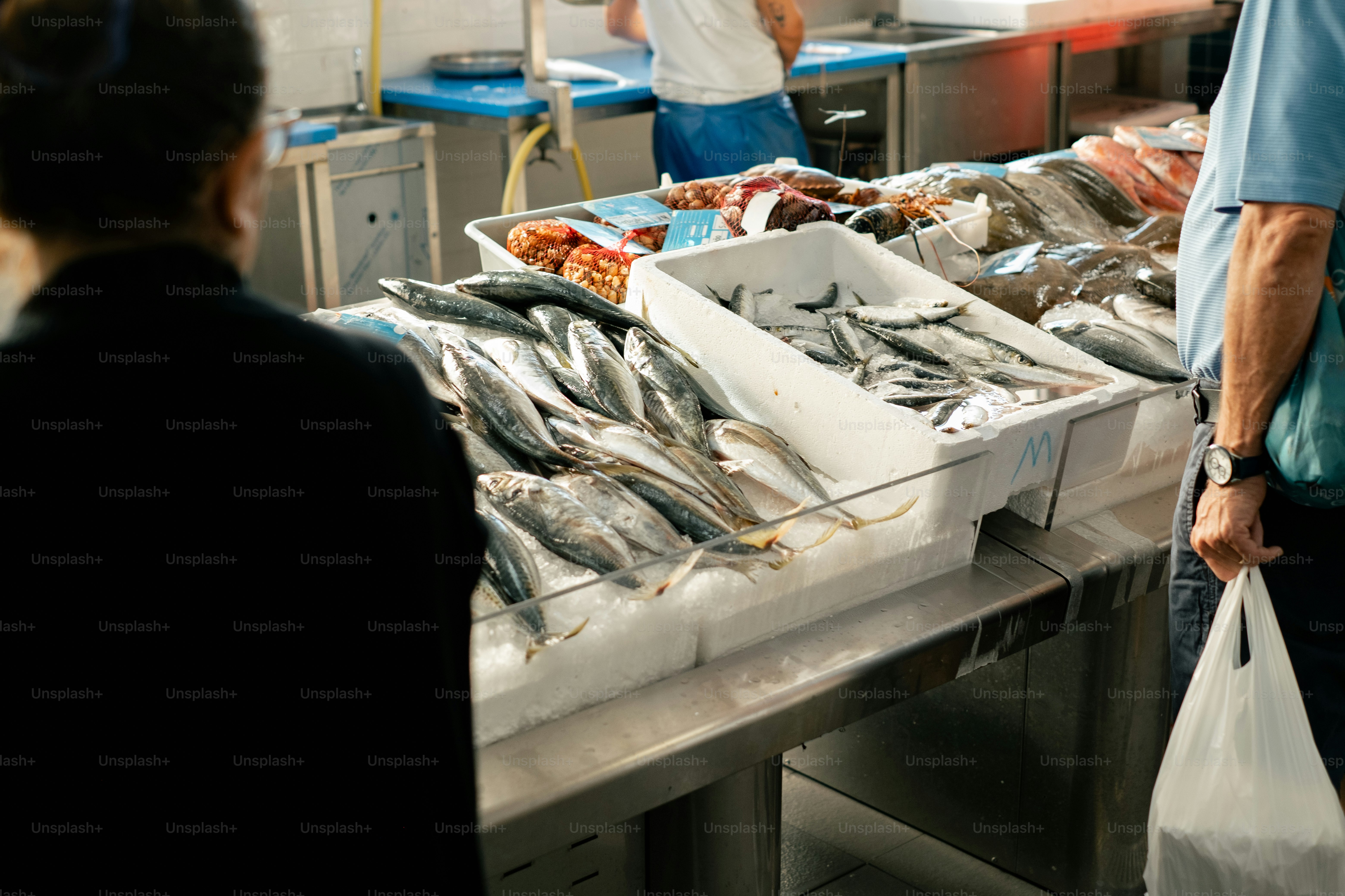 Customers browse fresh fish at a market stall.
