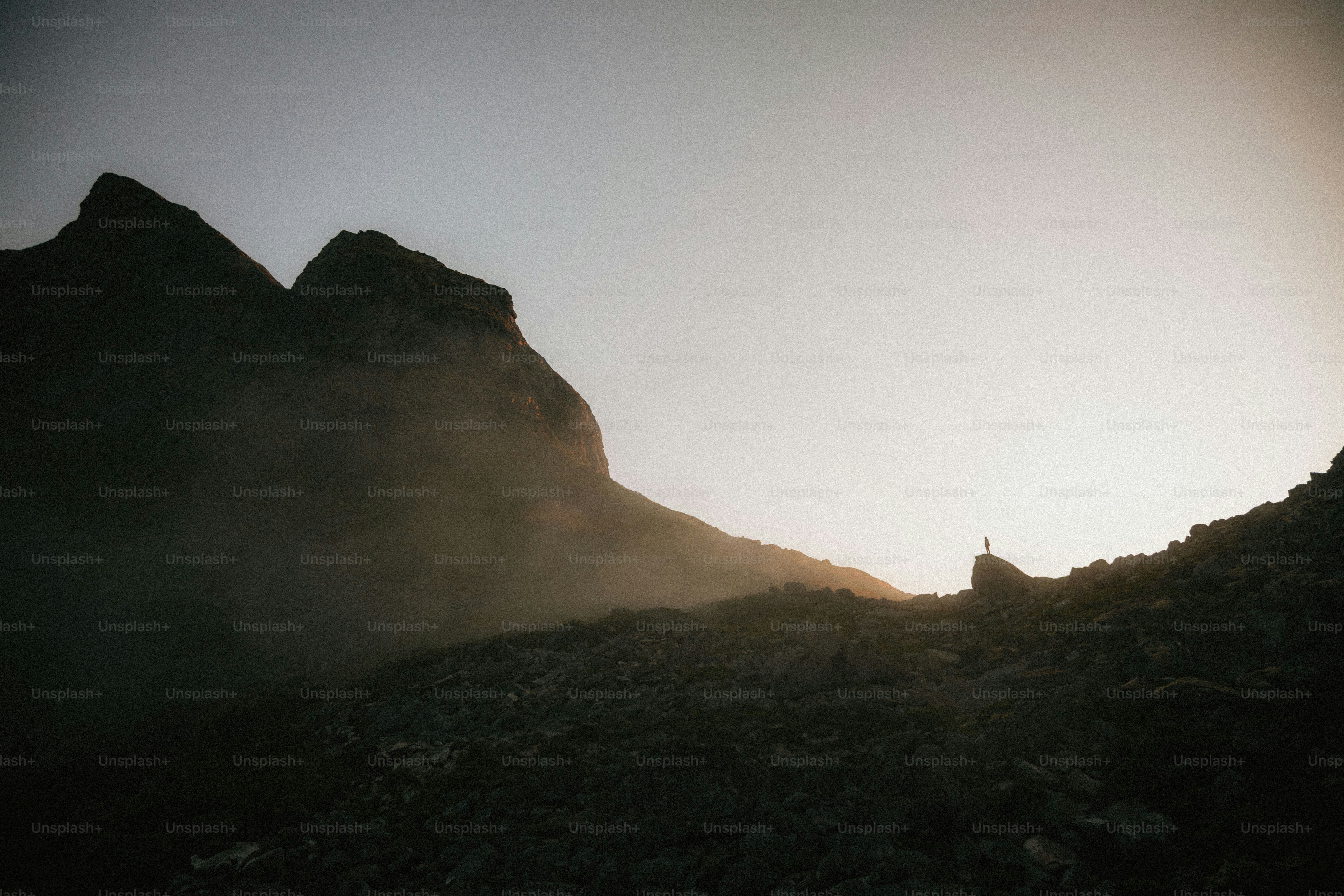 Silhouette d’une personne sur une montagne rocheuse au lever du soleil