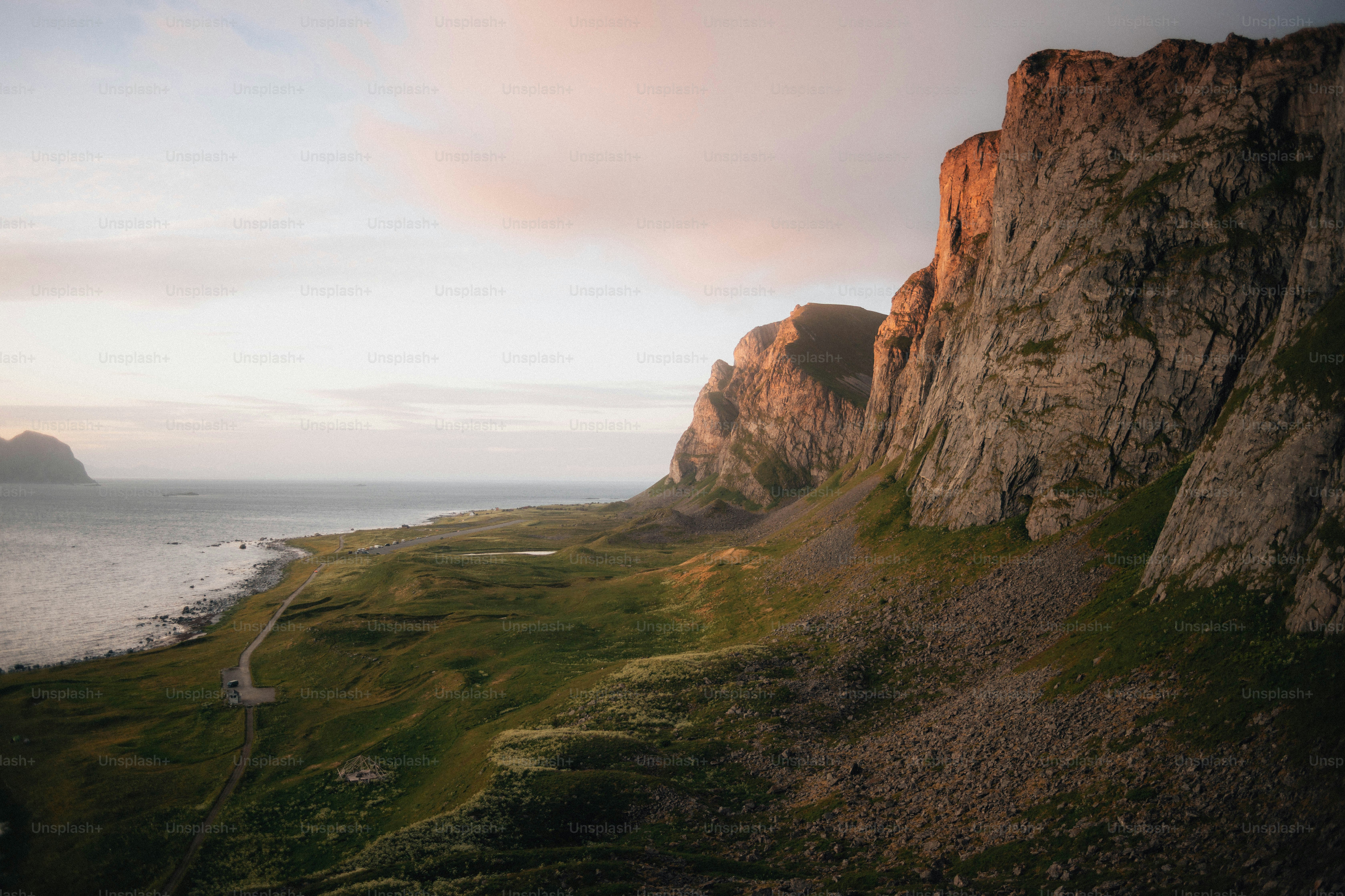Des falaises déchiquetées surplombent un paysage côtier verdoyant au coucher du soleil.