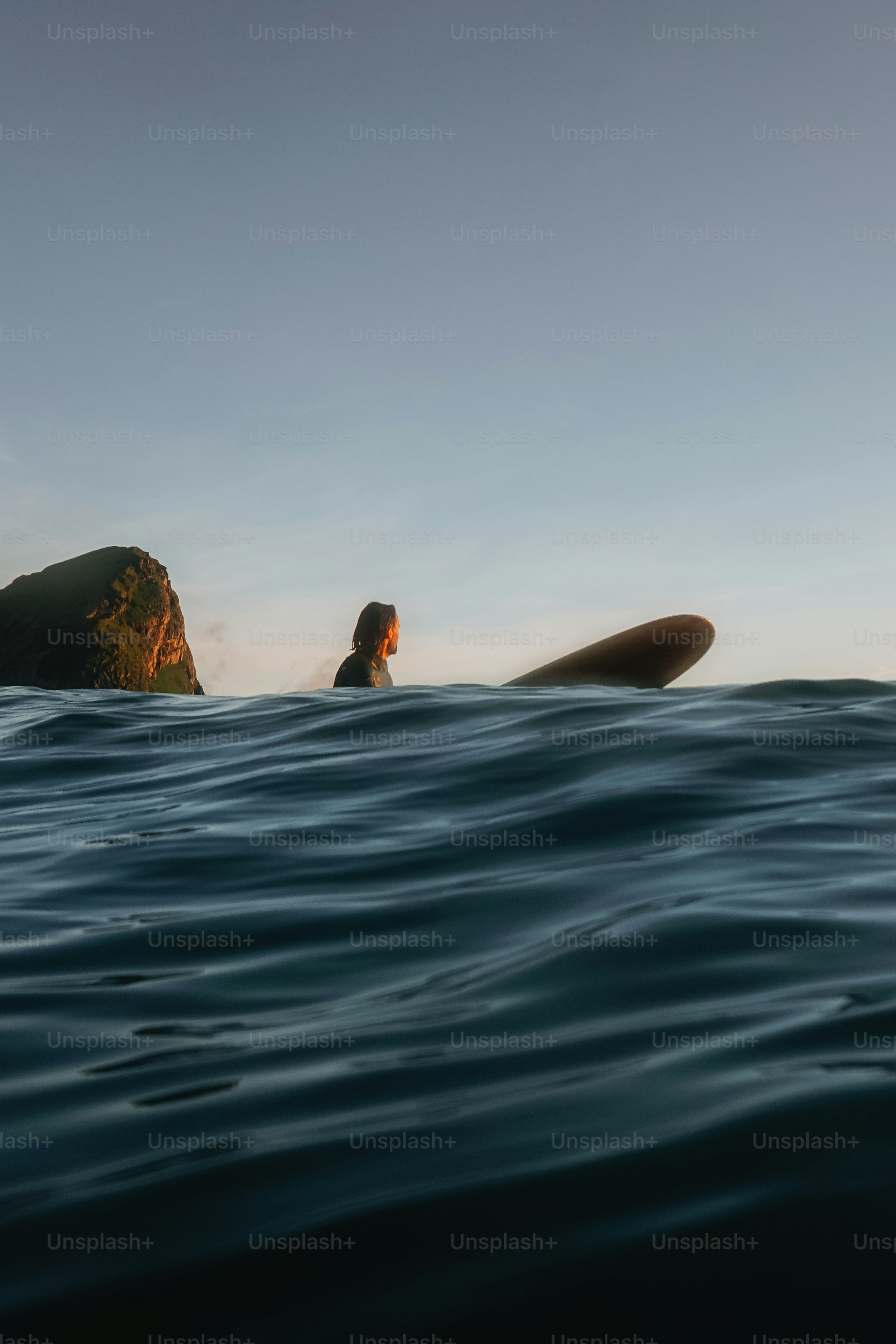 Surfeur dans l’océan avec planche de surf au coucher du soleil