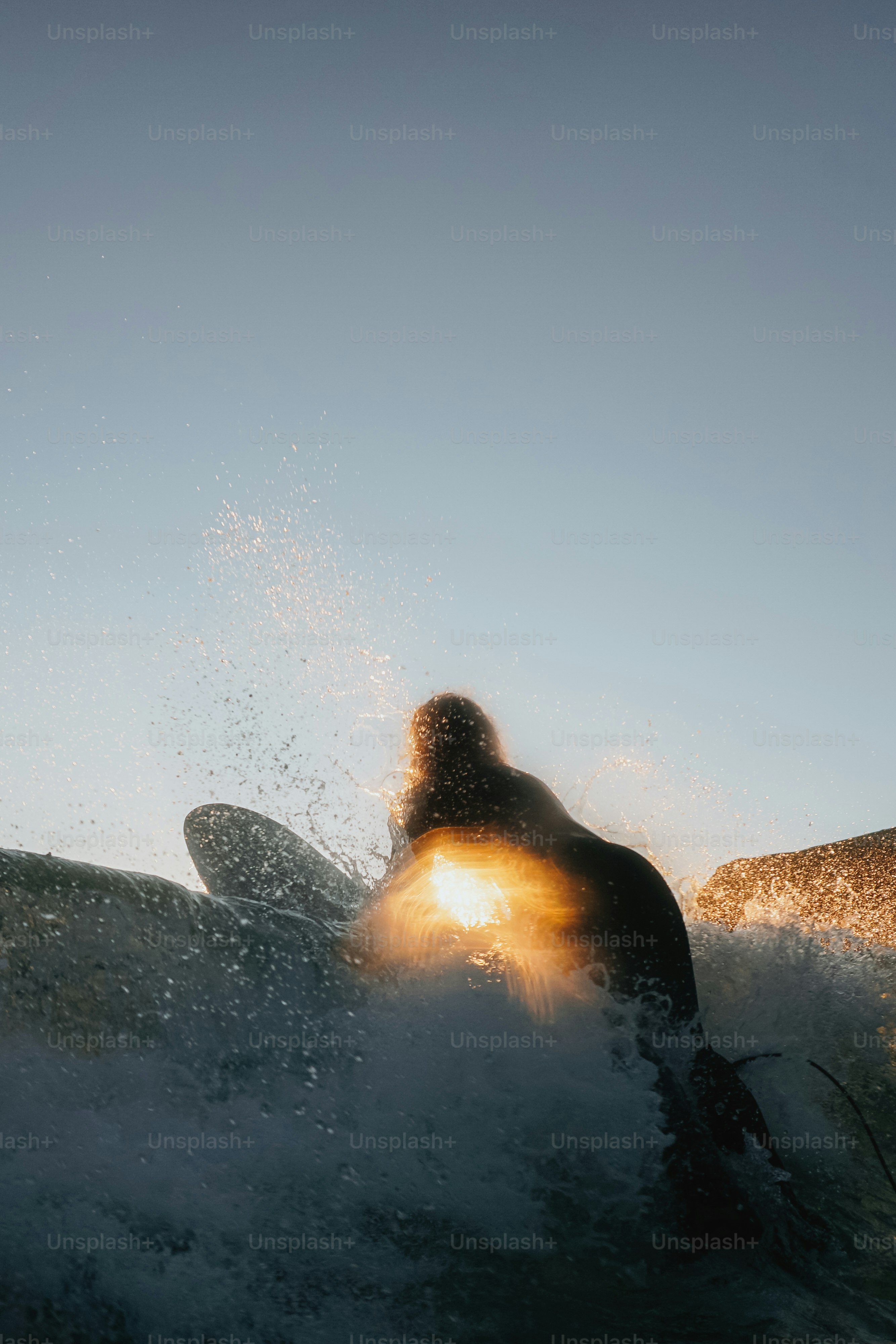 Surfer, der sich in den Wellen des Ozeans gegen die Sonne abhebt