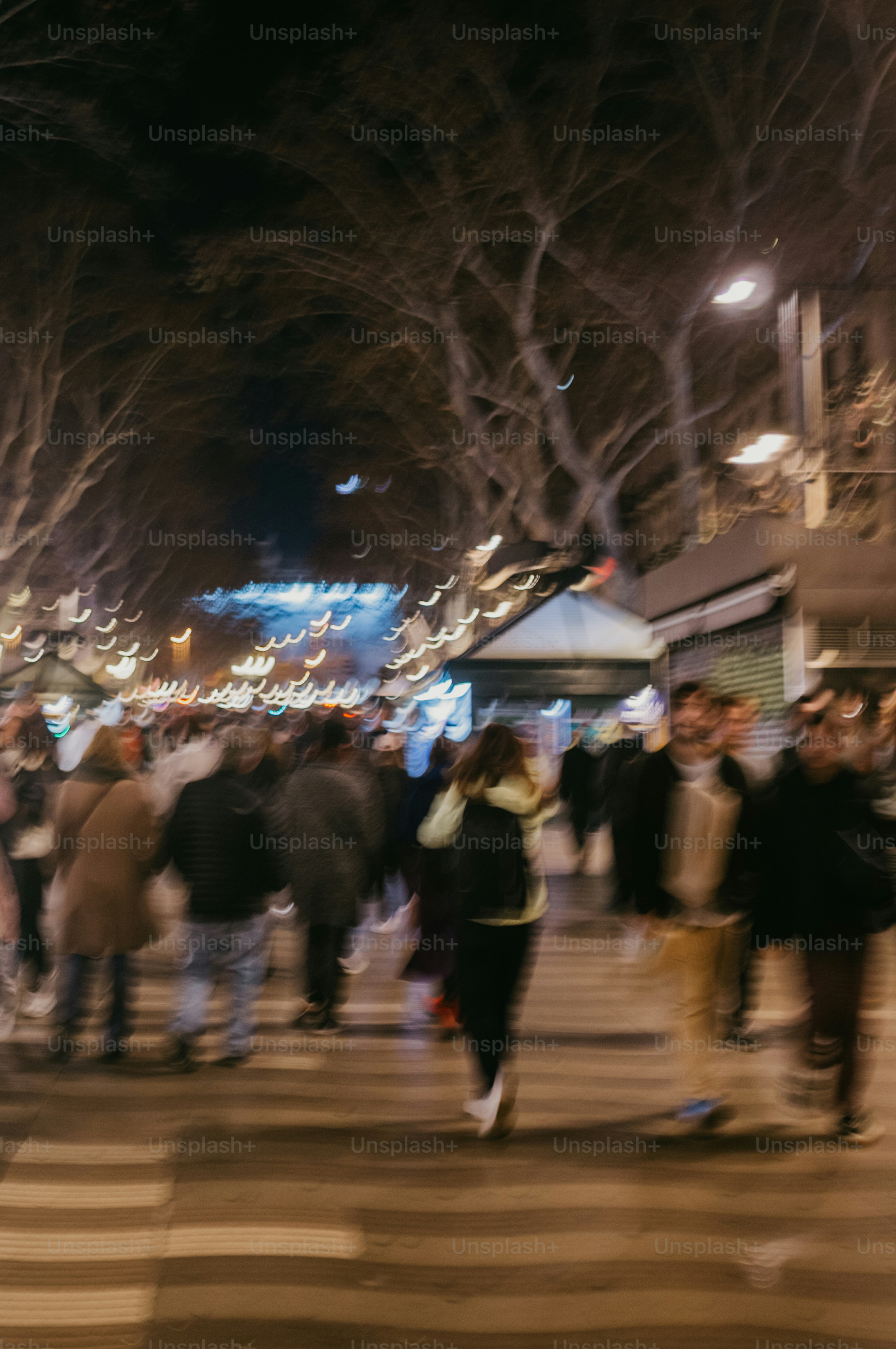 Blurred crowd walking on a street at night.
