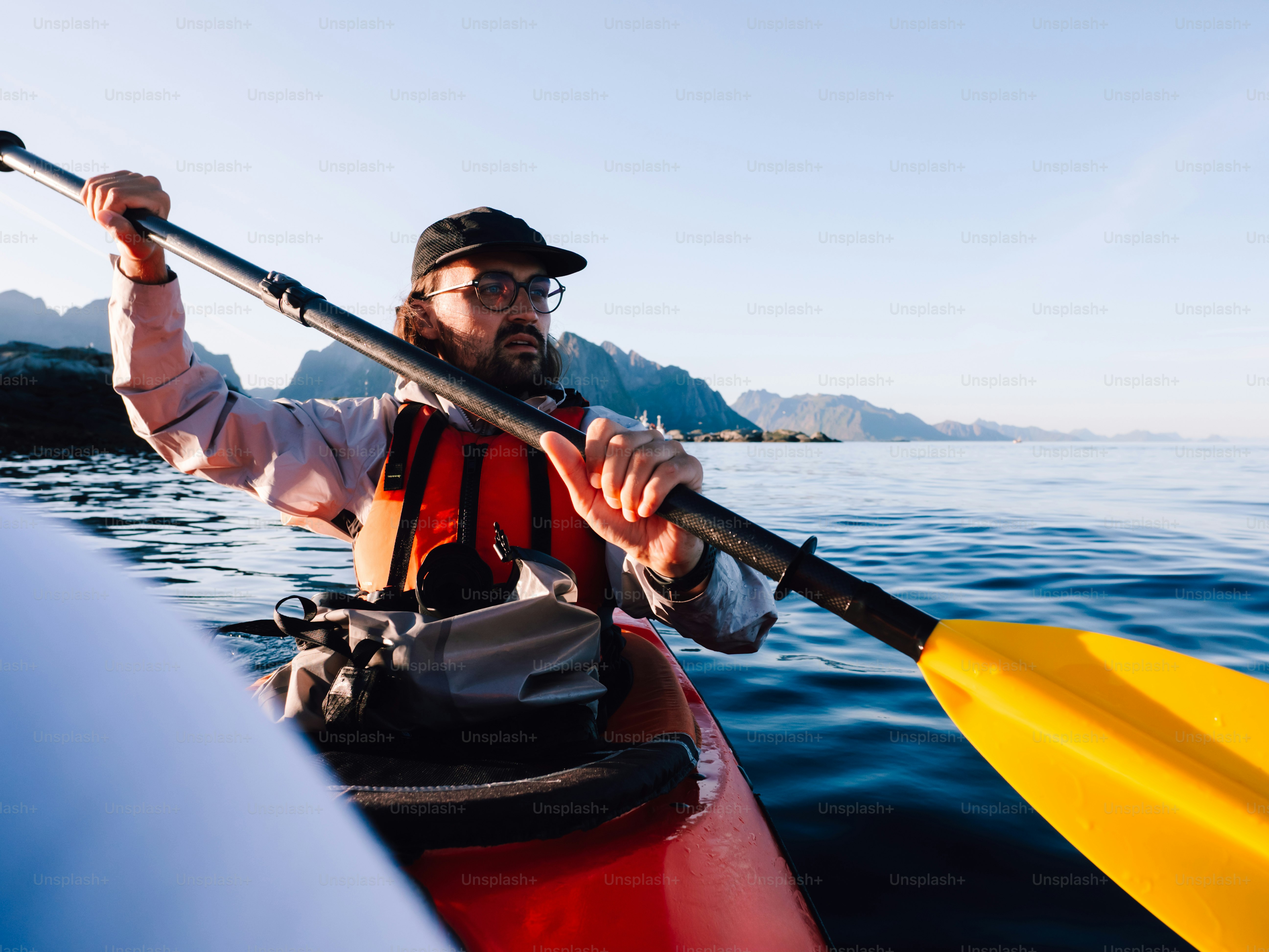 Hombre navegando en kayak en aguas tranquilas con montañas