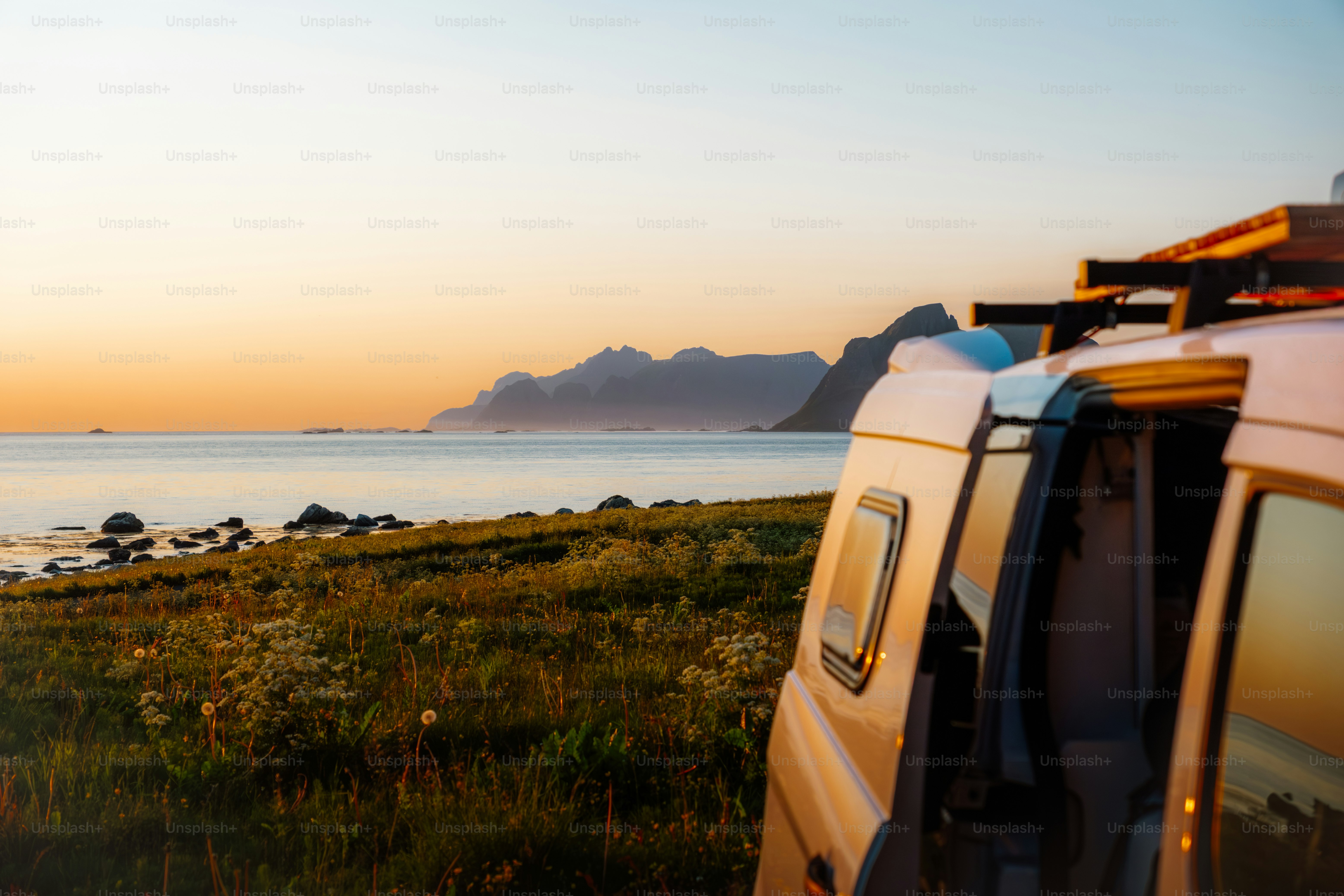 Camper van parked by the ocean at sunset