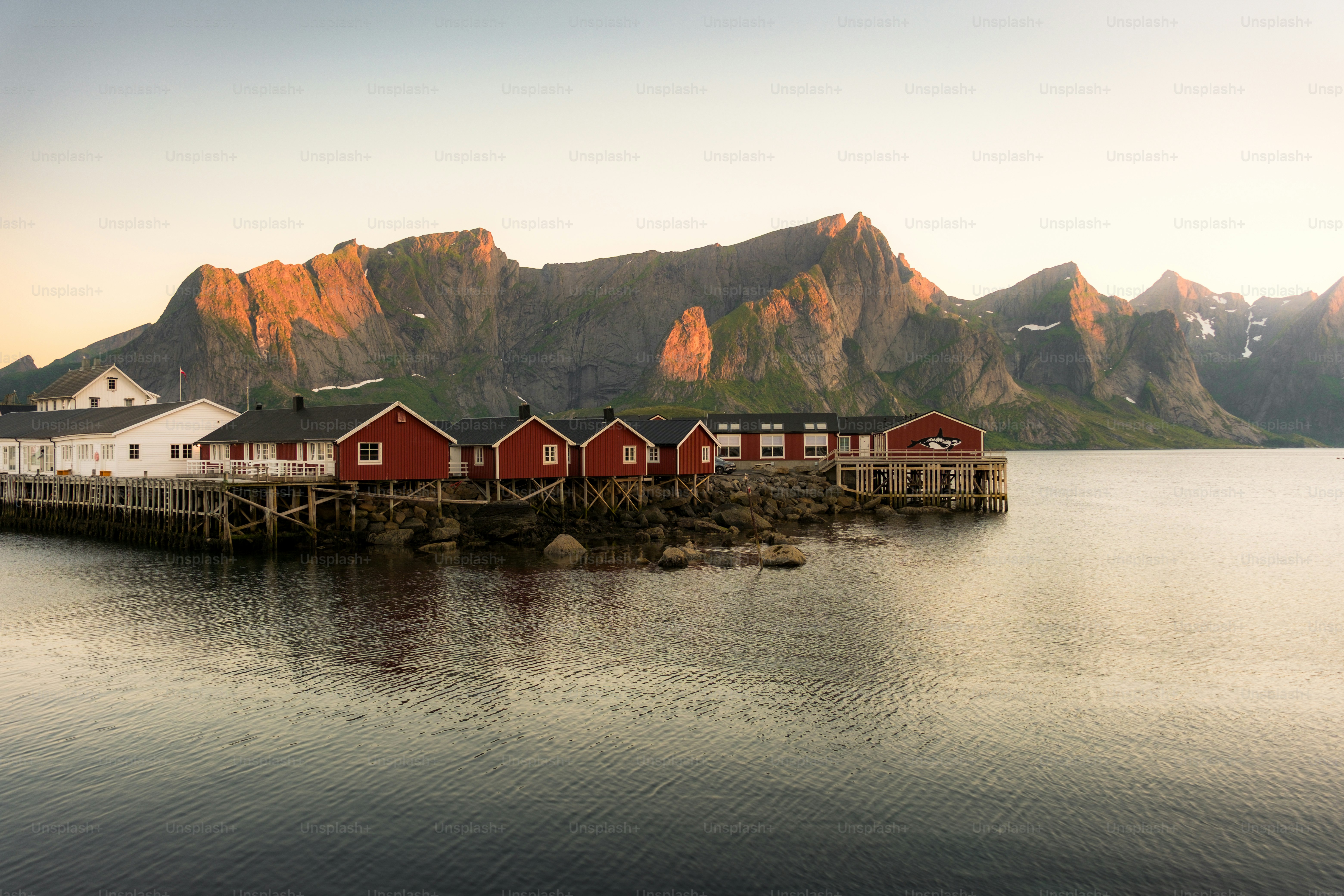 Cabines de pesca vermelhas em um cais por um mar calmo.