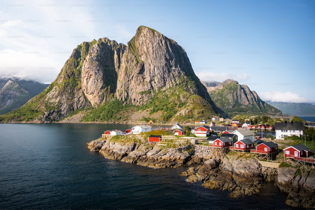 Coastal village with red houses near a large mountain.