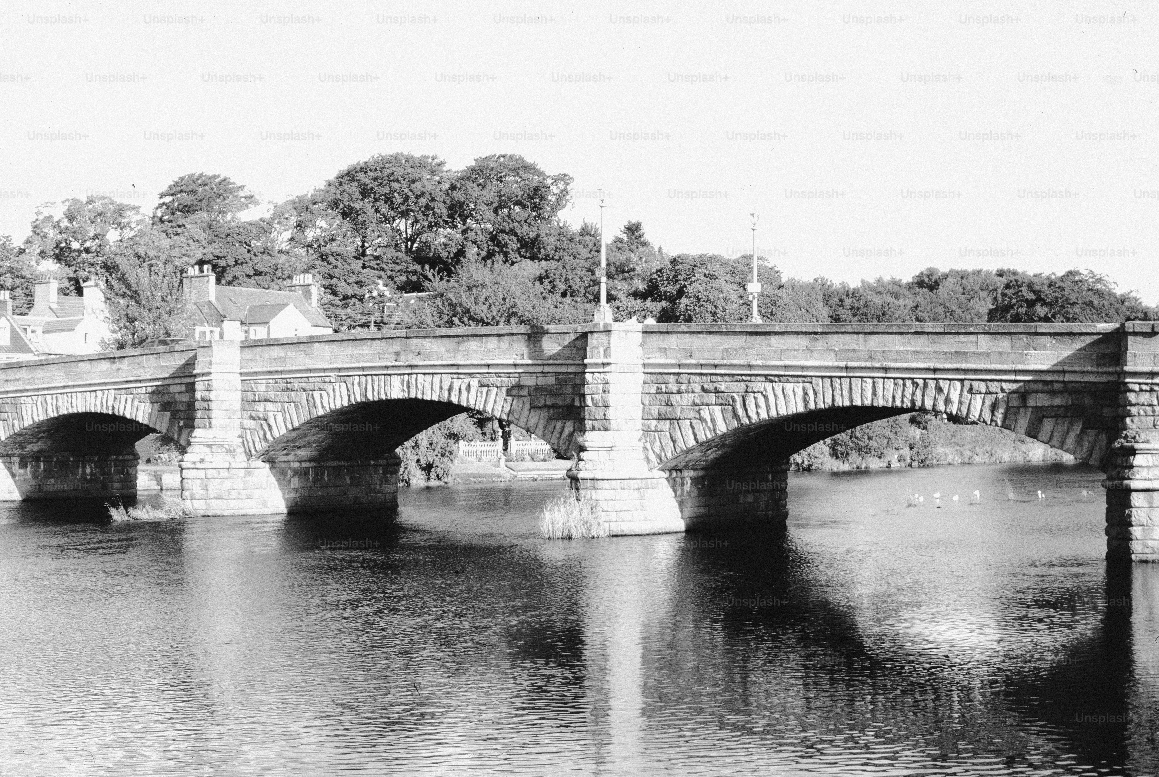 Stone bridge with arches over a calm river.