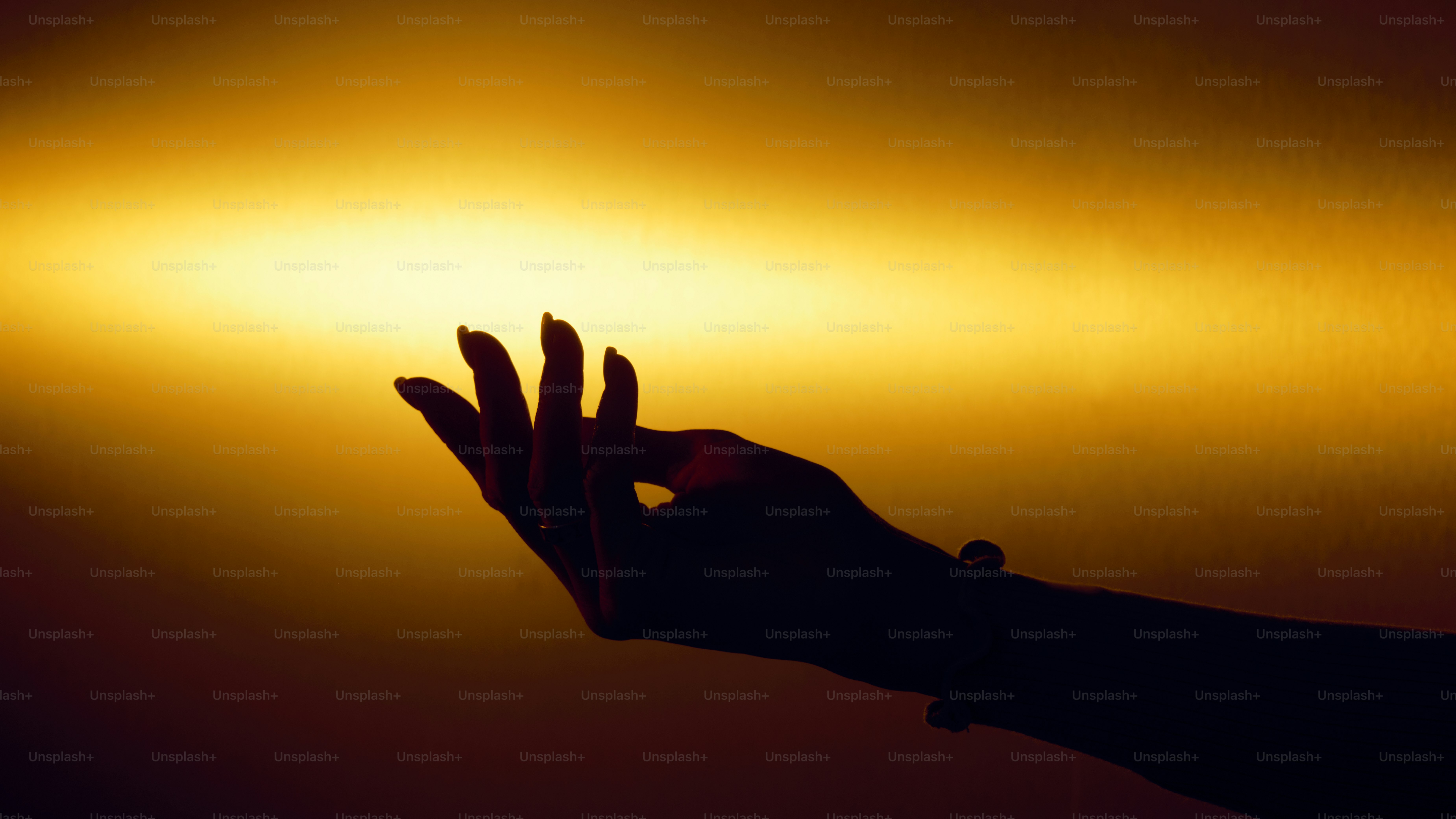 Silhouette of a hand reaching out towards light