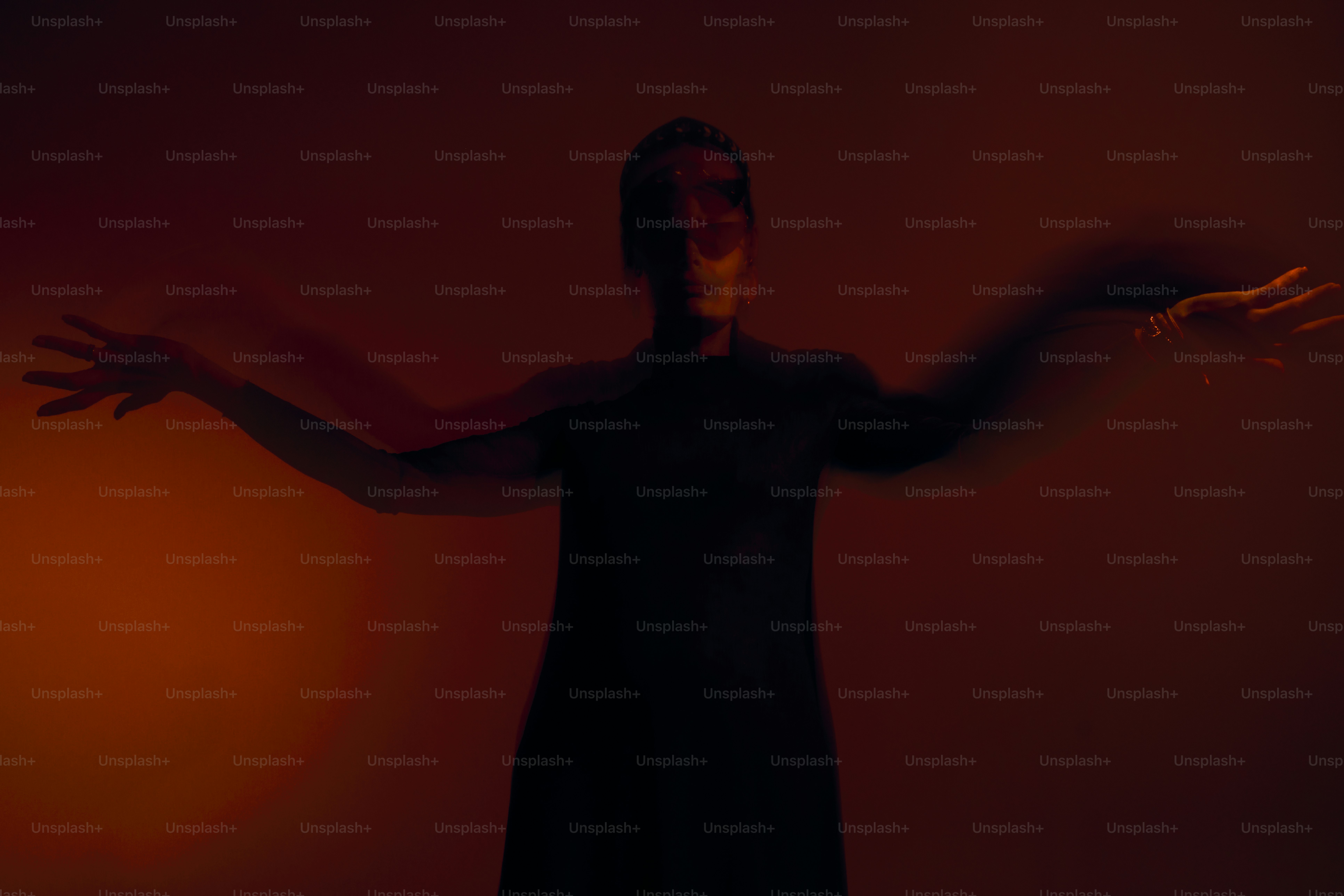 A silhouetted figure with arms outstretched against a dark background ...