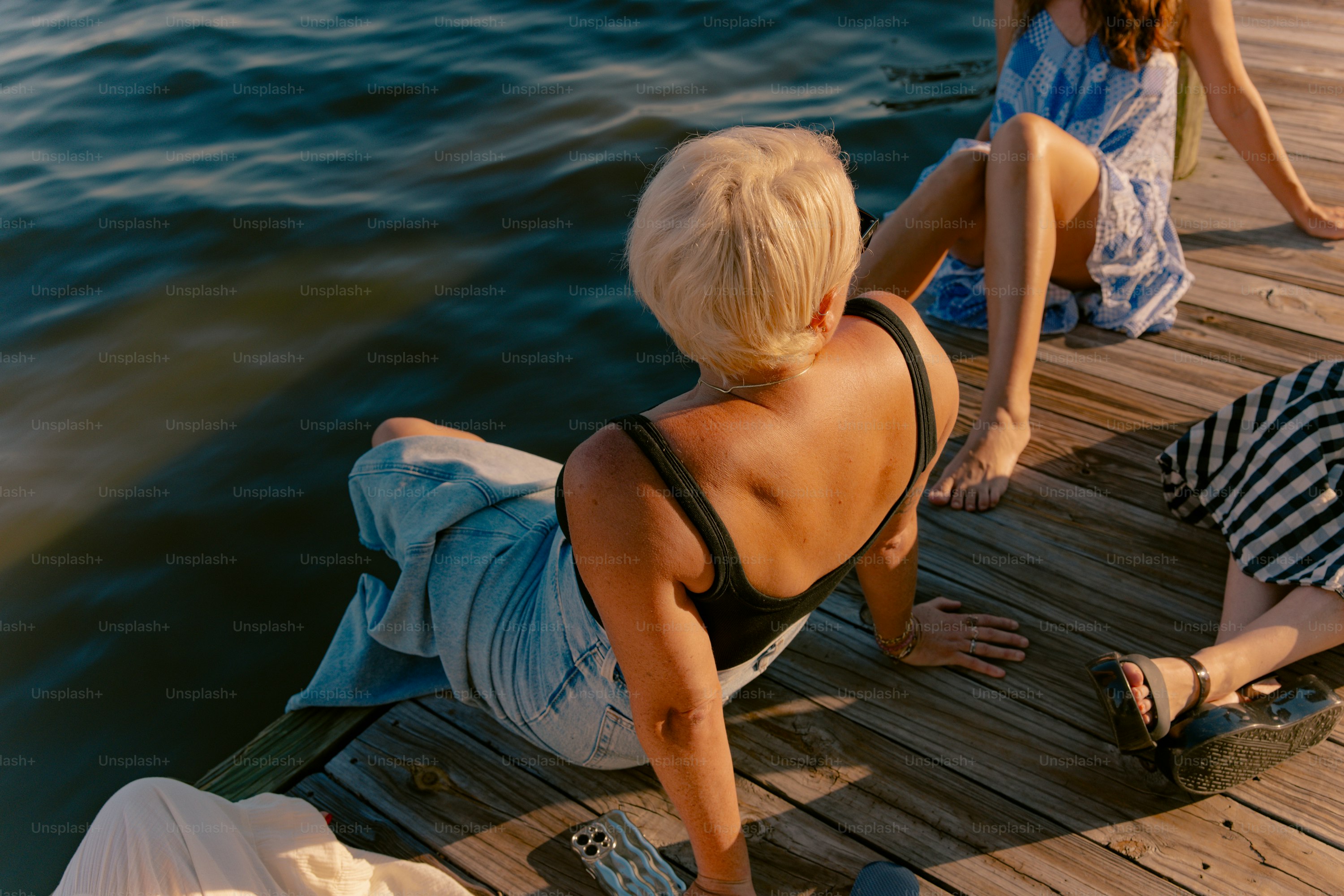 People relaxing on a wooden dock by the water