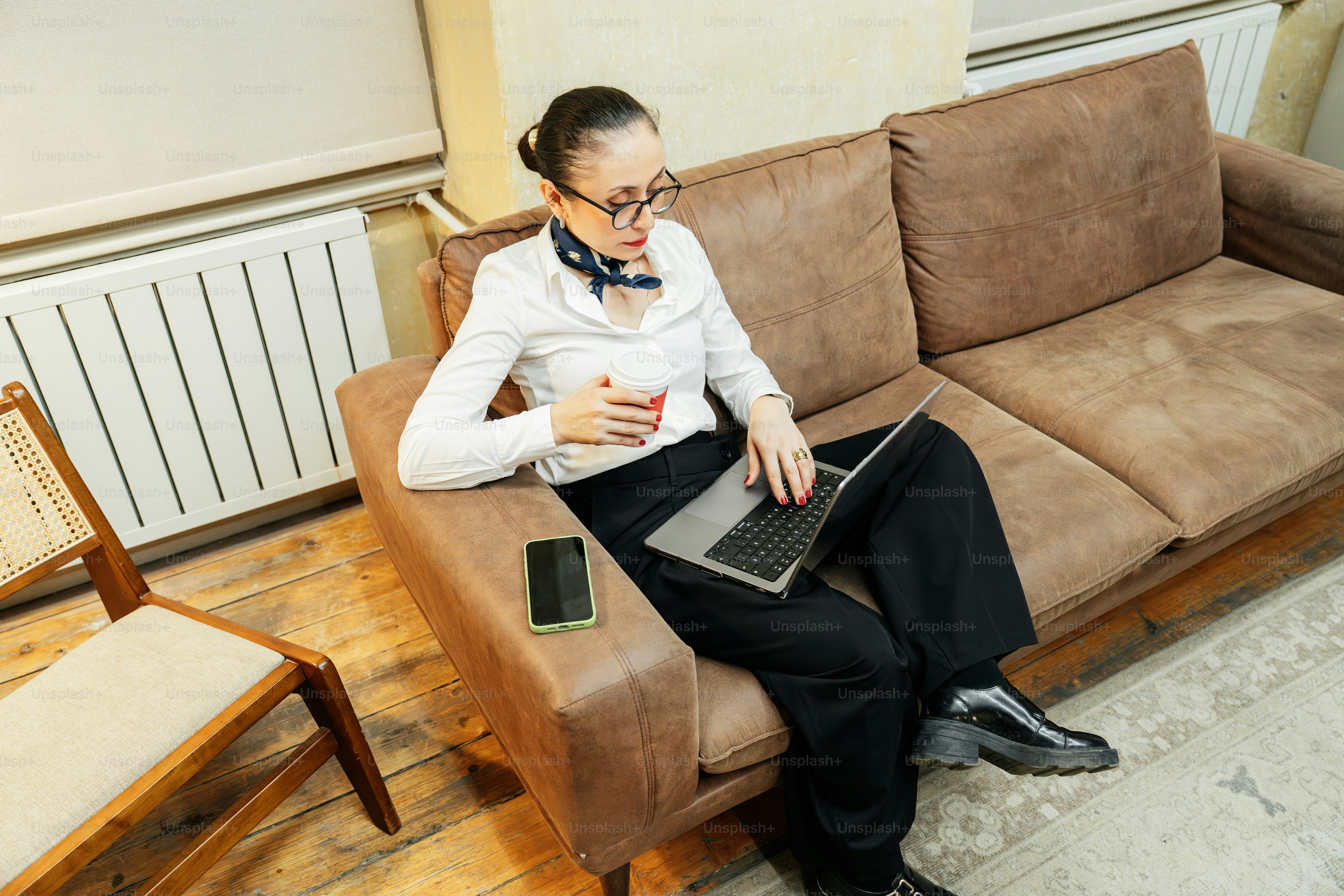 Frau, die am Laptop arbeitet, während sie auf dem Sofa sitzt