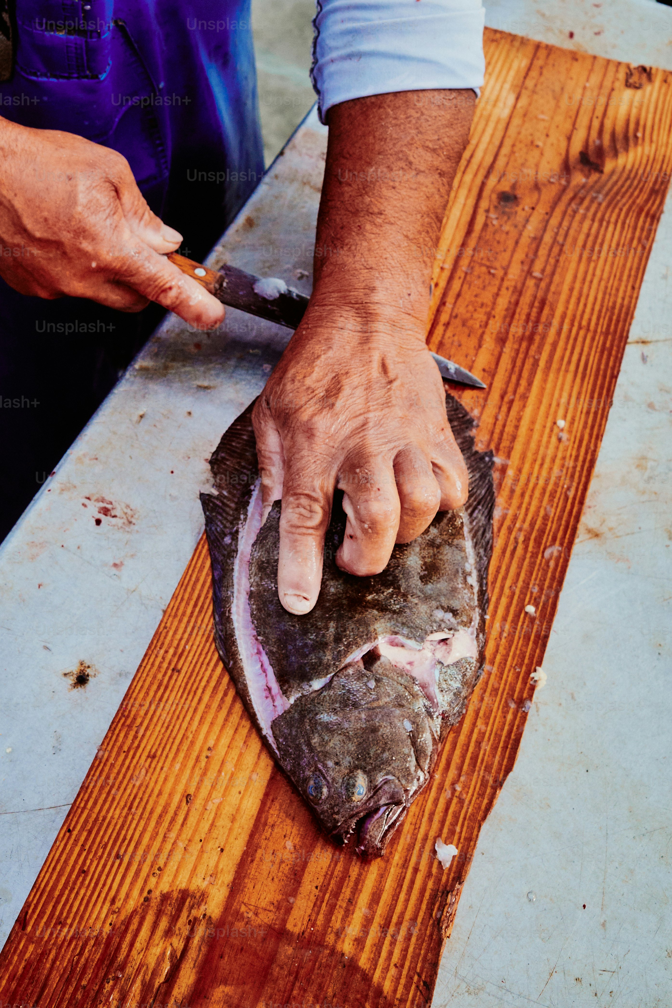 Hands preparing a flatfish on a wooden board