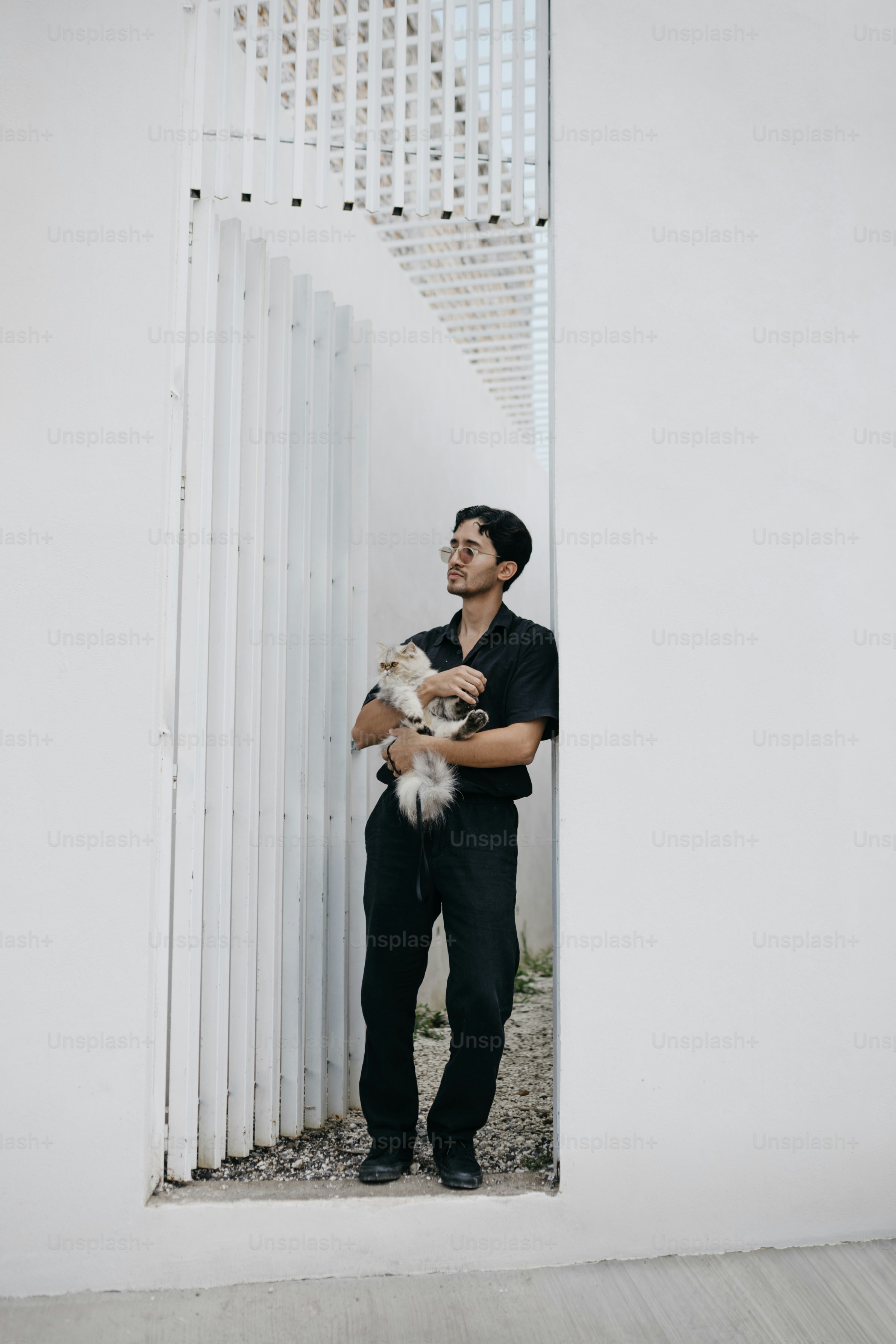 Man in black holding a fluffy cat outdoors.