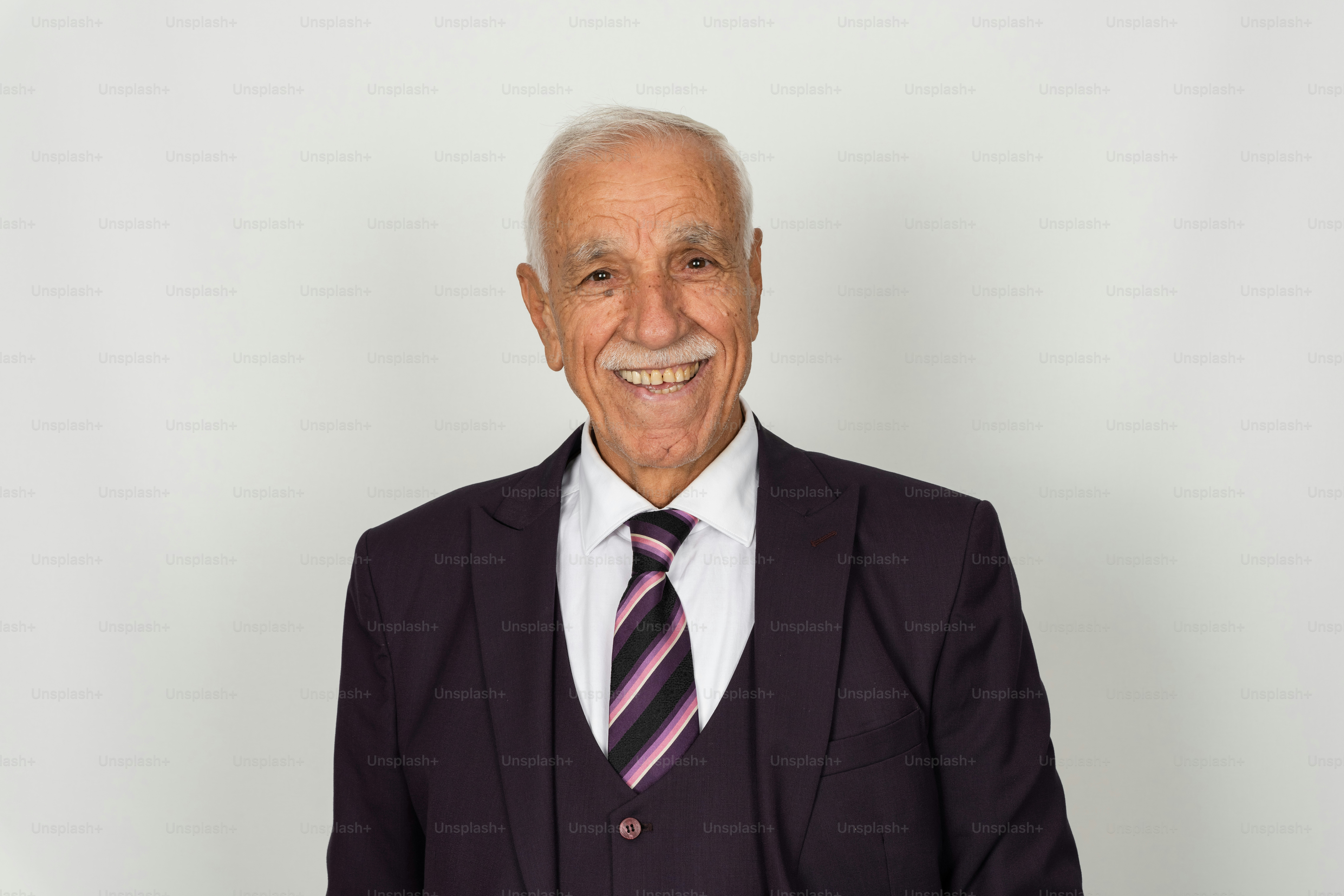 Um homem idoso de terno sorri calorosamente.