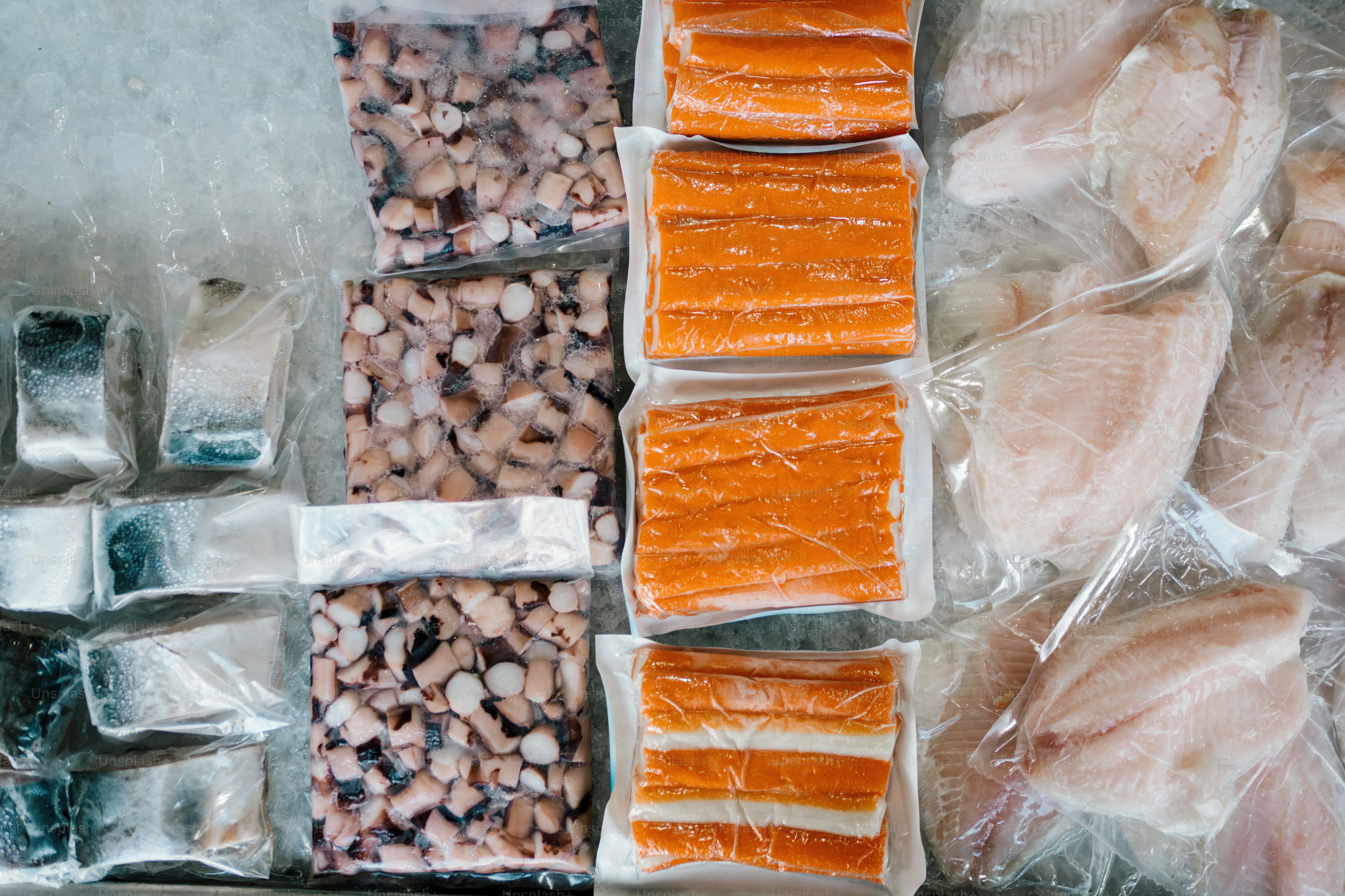 Assortment of frozen seafood products in plastic packaging.