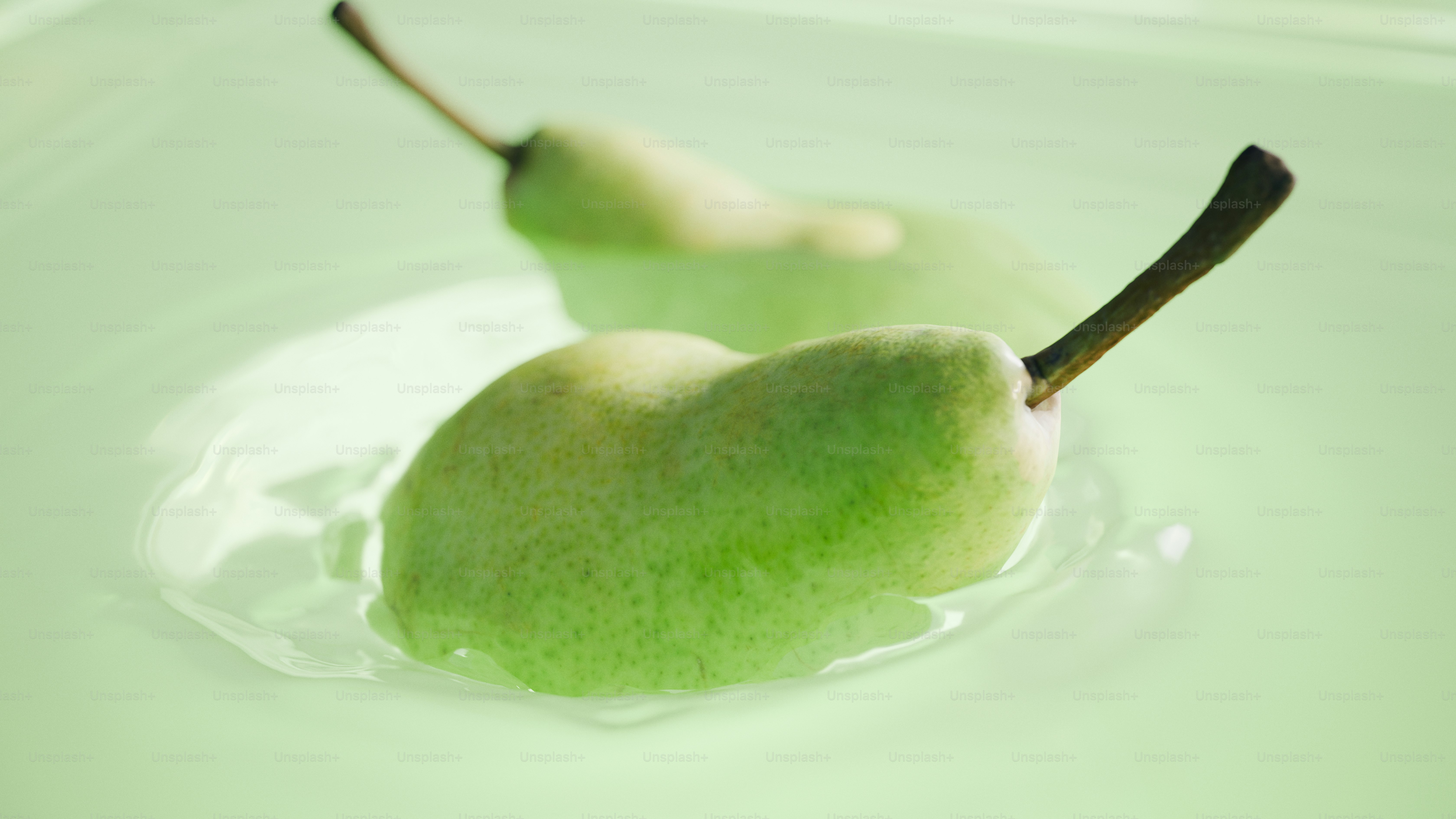Two green pears floating in clear liquid.