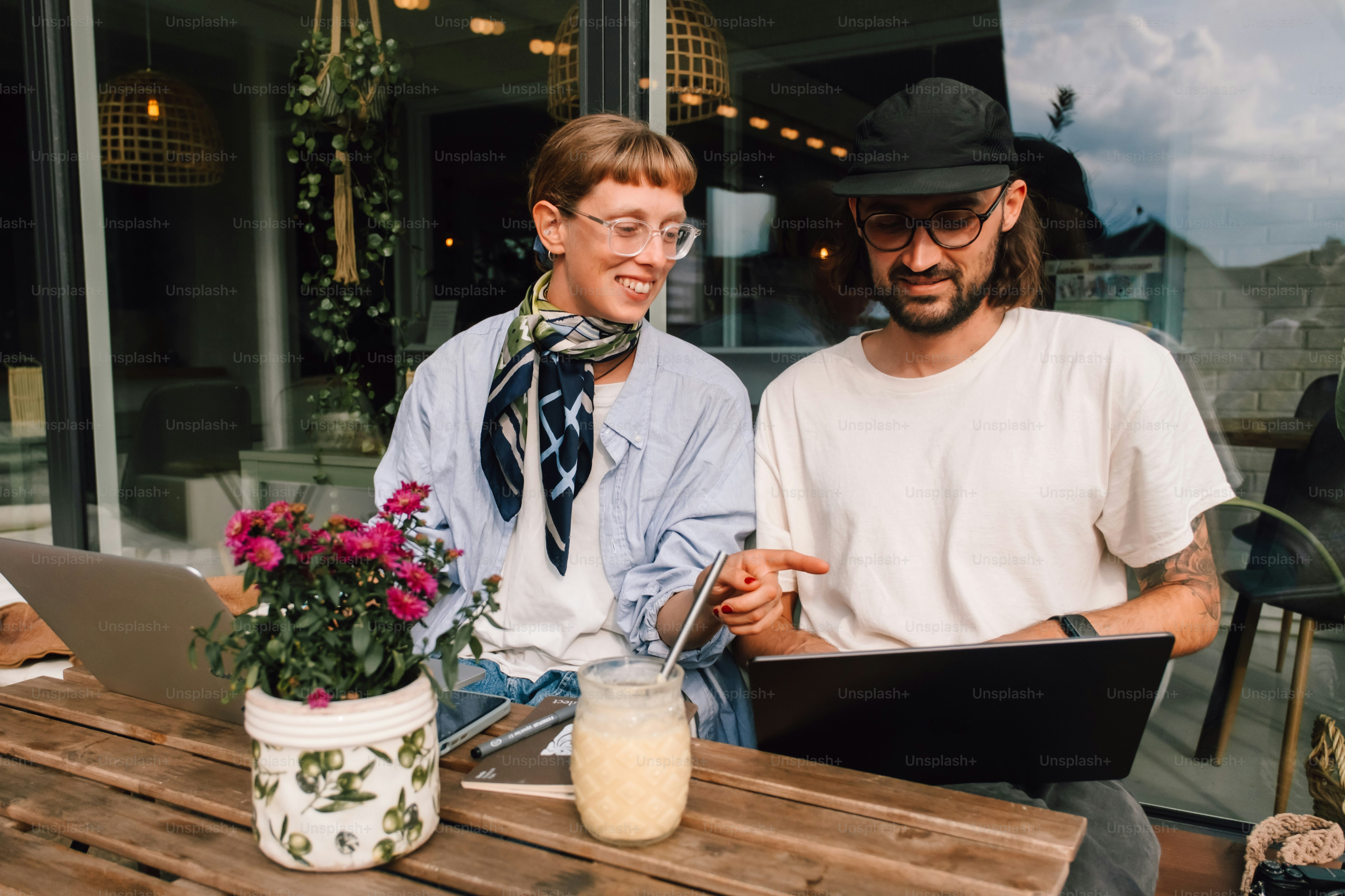 Two people working on laptops at an outdoor cafe.