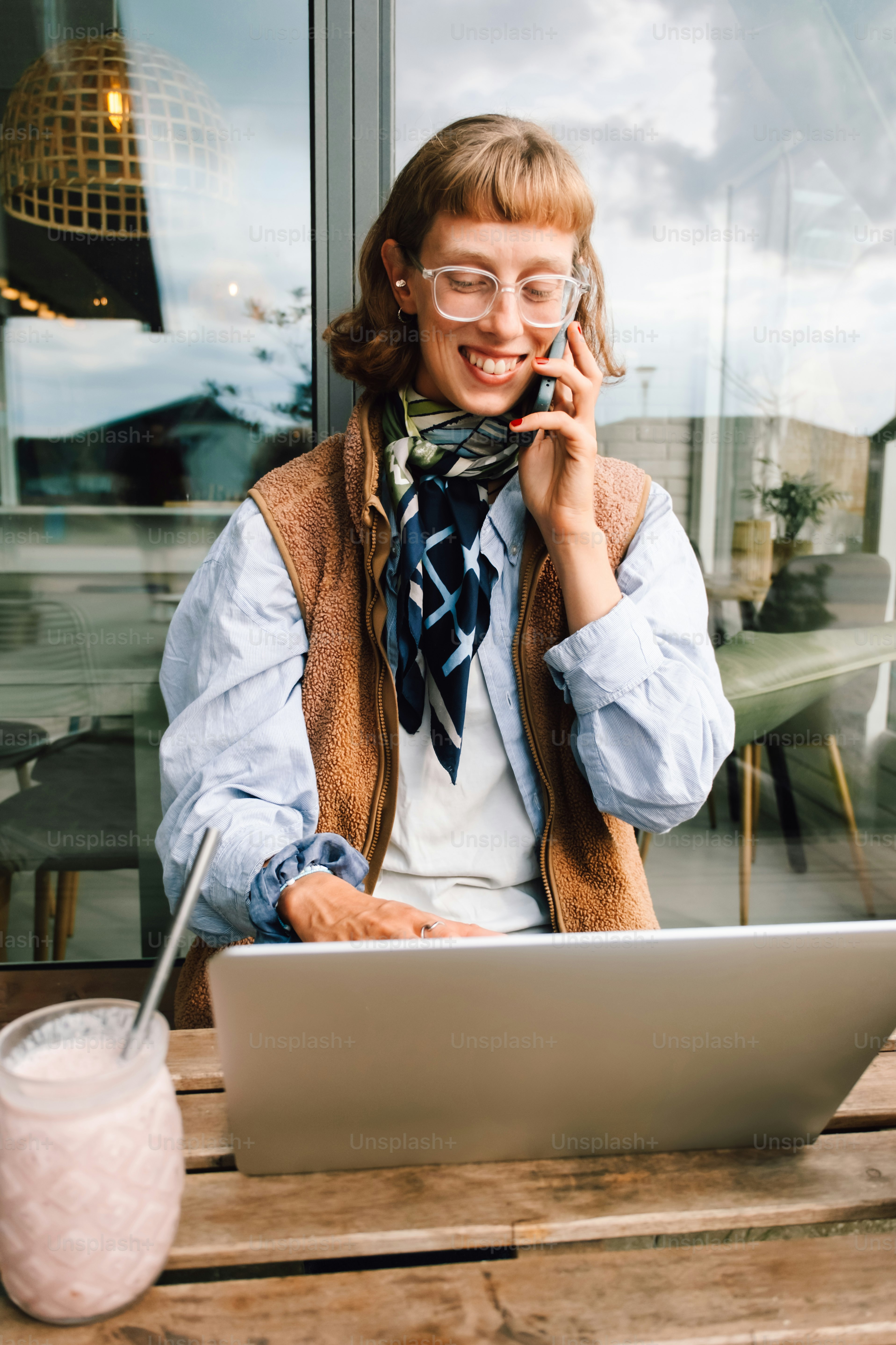 Woman smiling while talking on phone with laptop