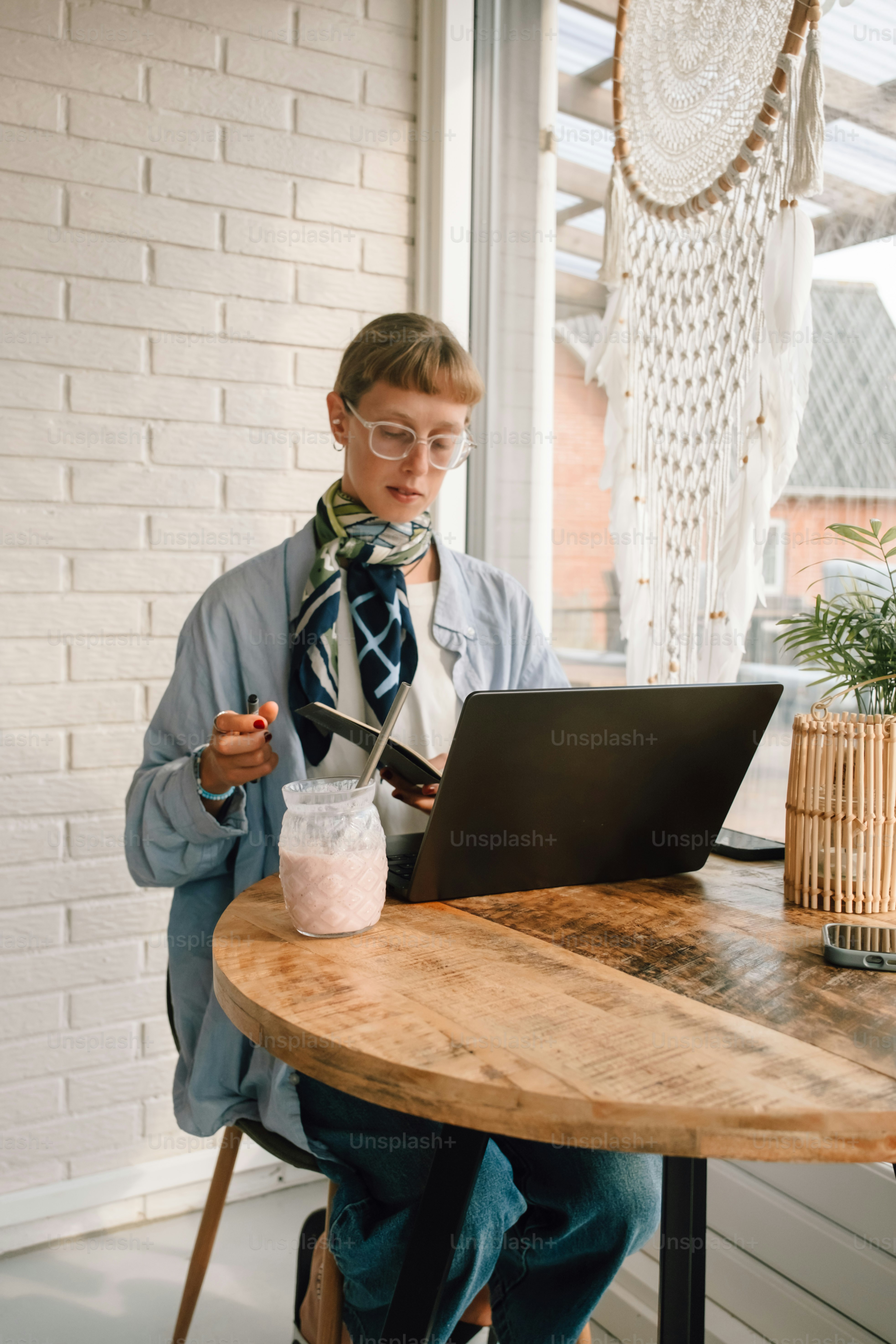 Woman working on laptop with food and drink.