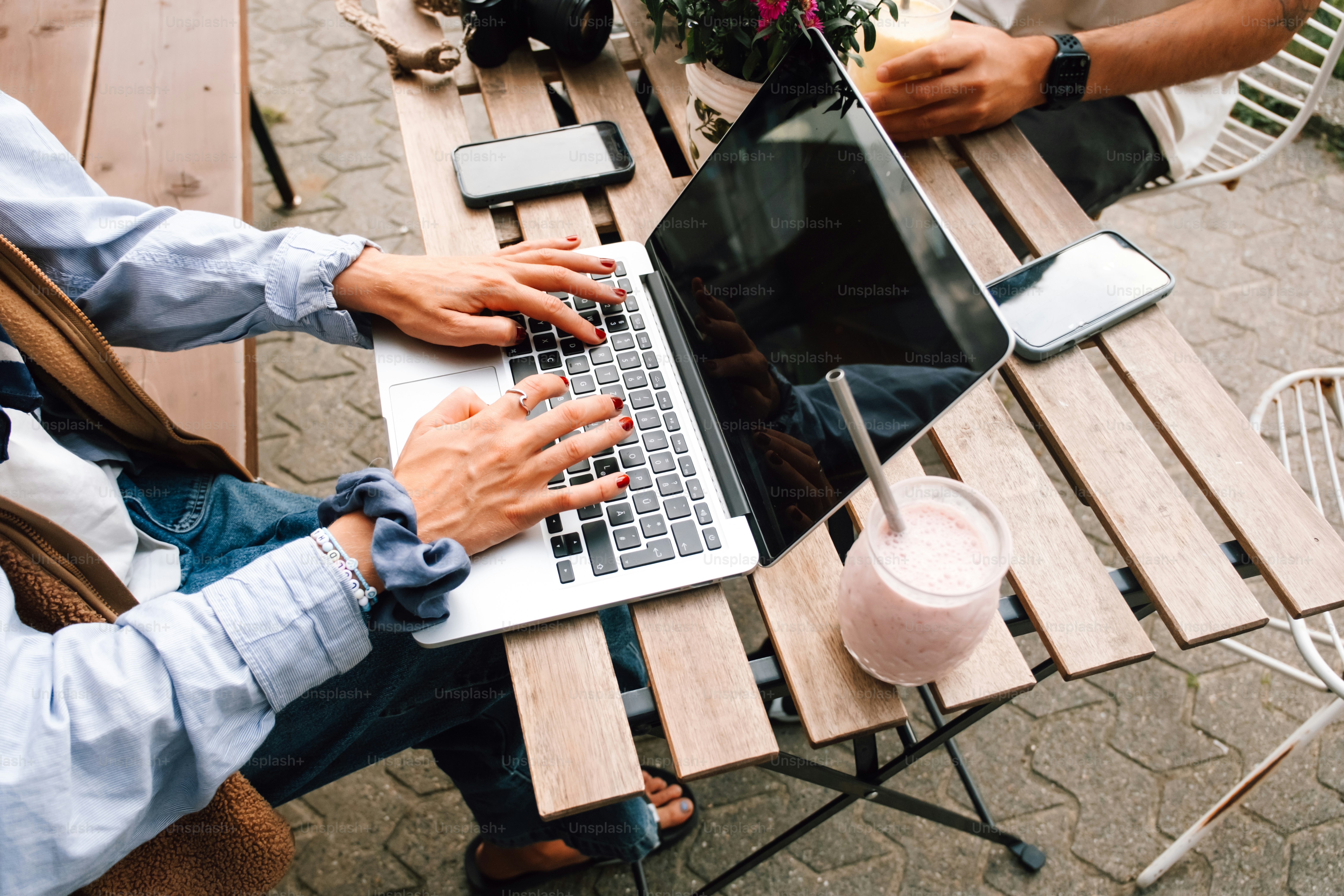 People working on laptops at an outdoor cafe table.