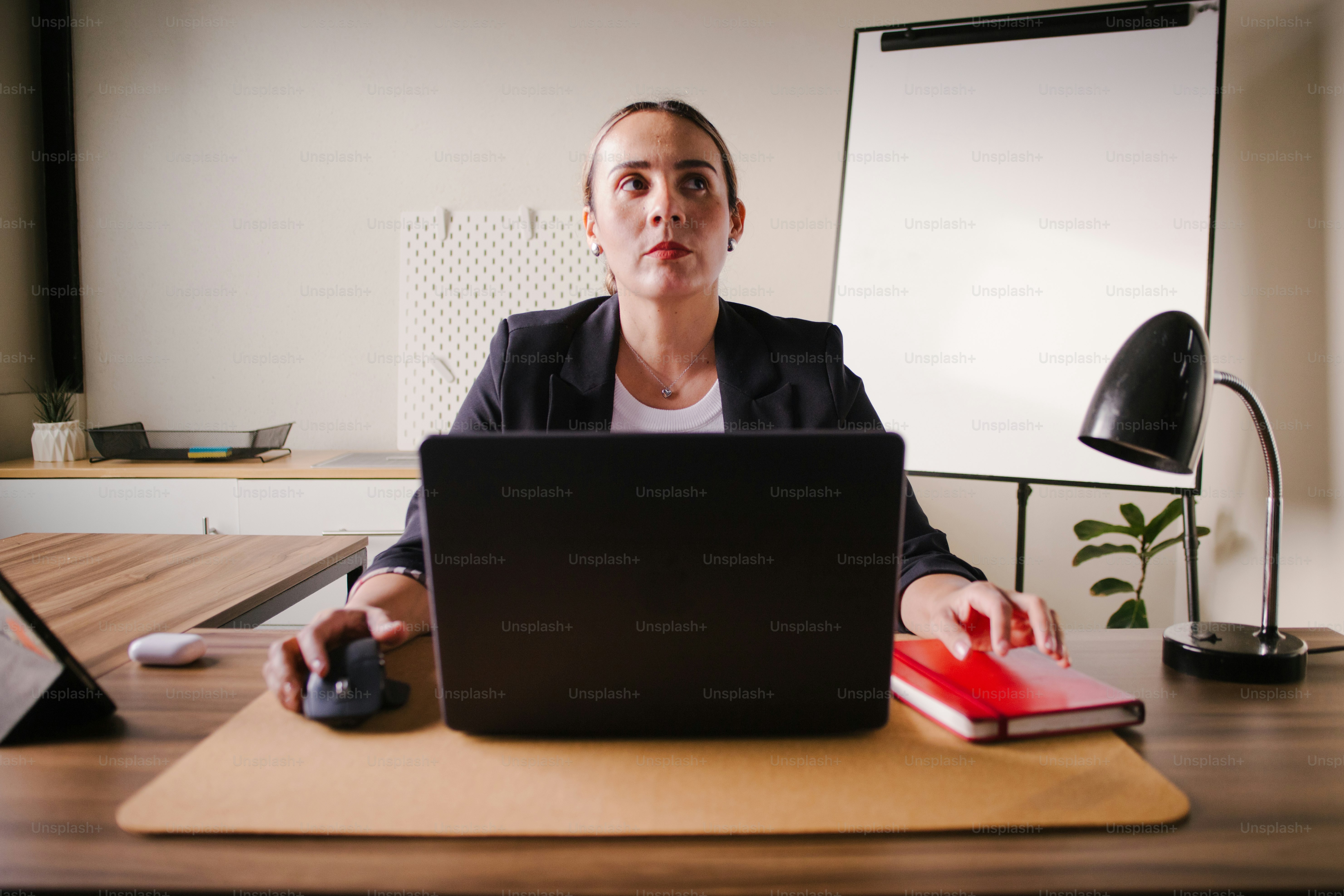 Femme travaillant à un bureau avec un ordinateur portable et un cahier.