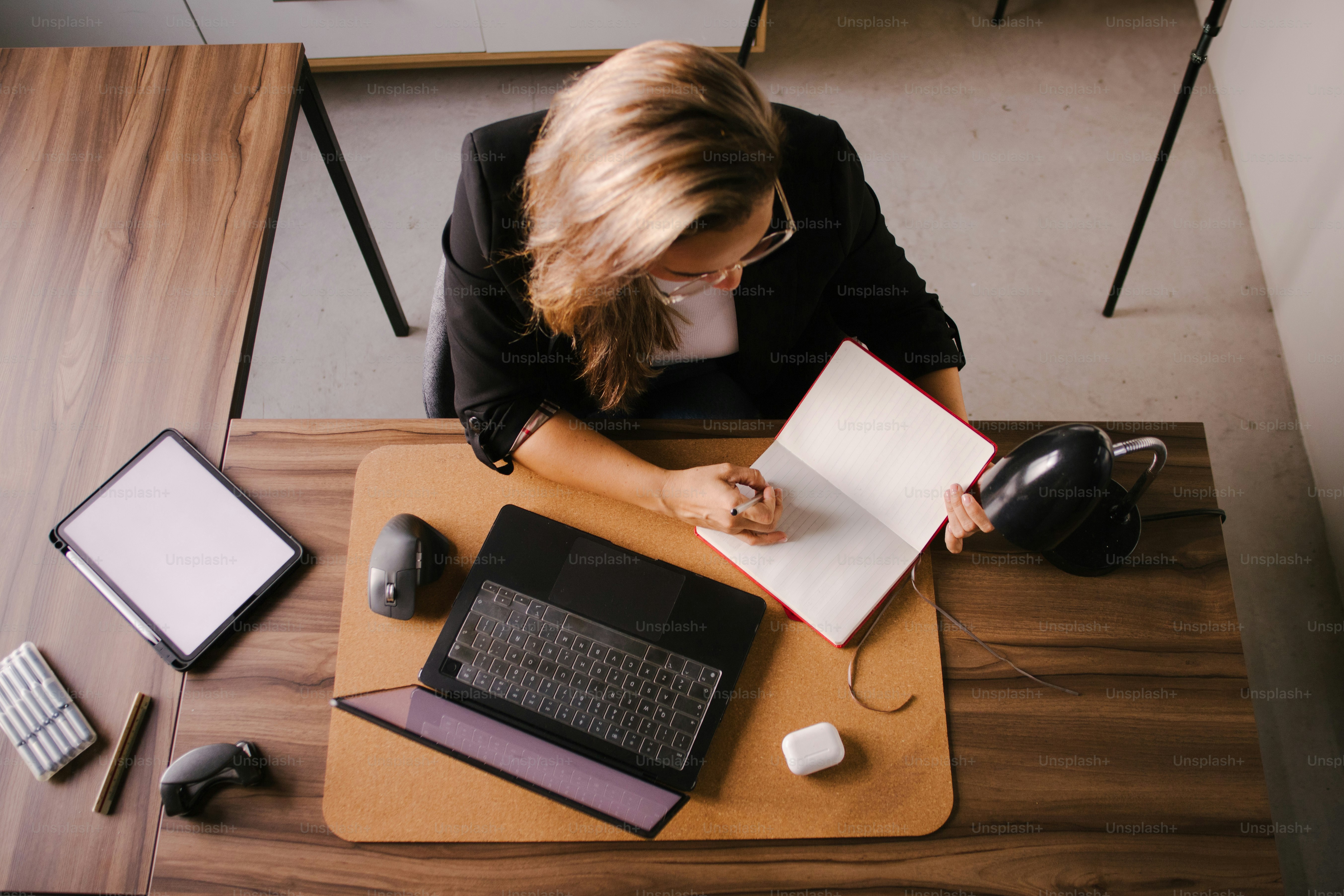 Femme écrivant dans un cahier au bureau avec ordinateur portable