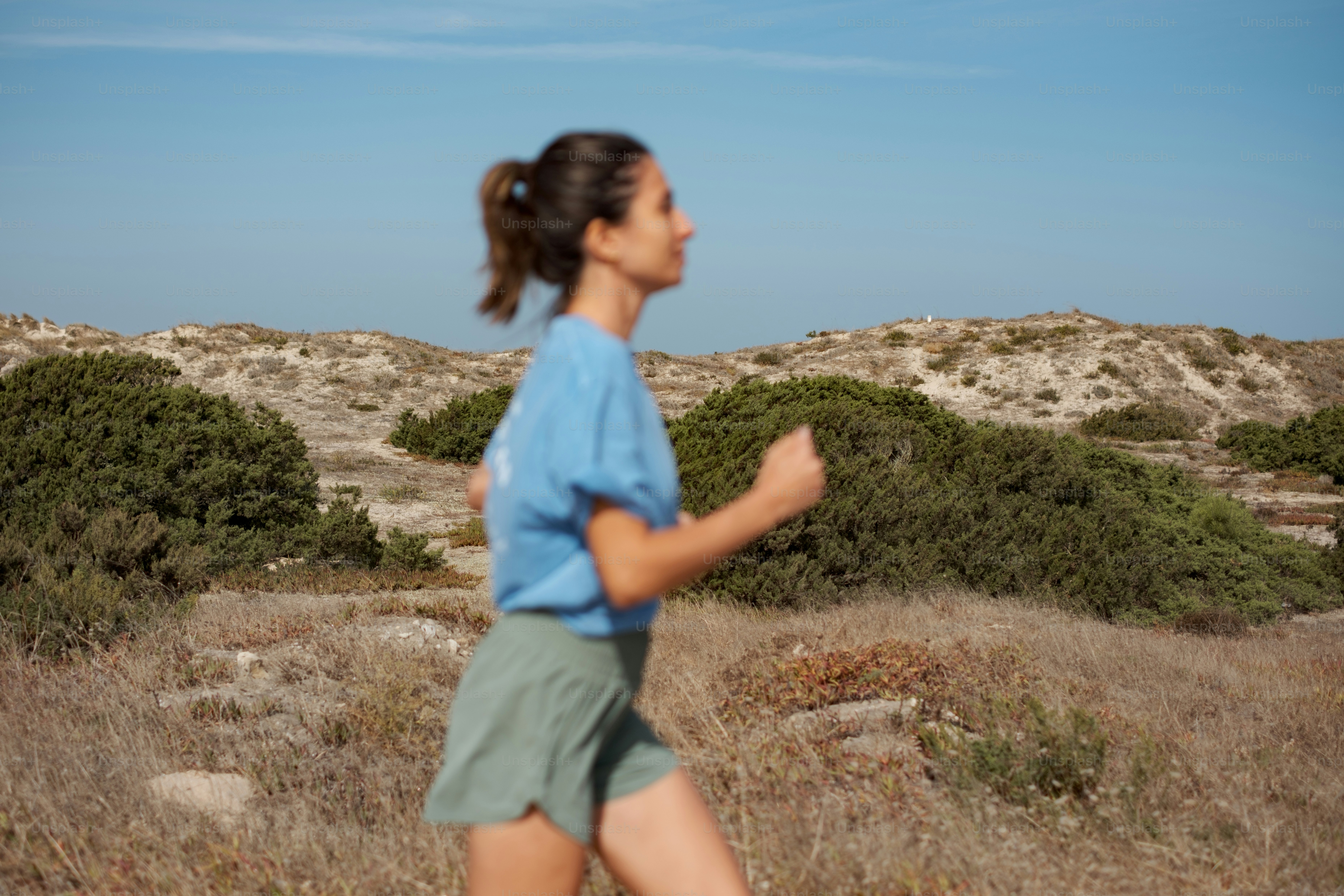 Woman jogging outdoors in a natural landscape.