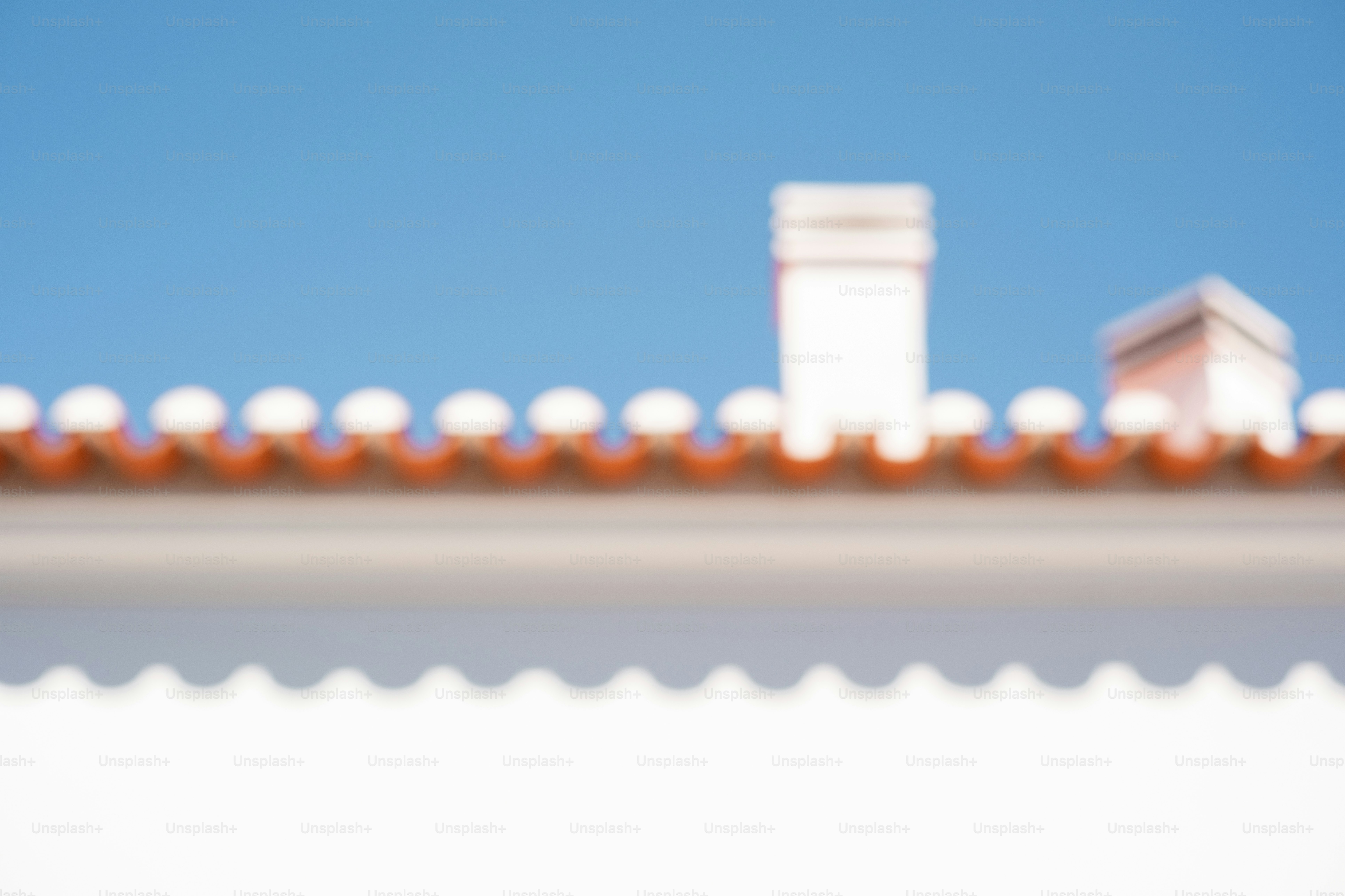 Dos chimeneas en un techo de tejas bajo un cielo azul