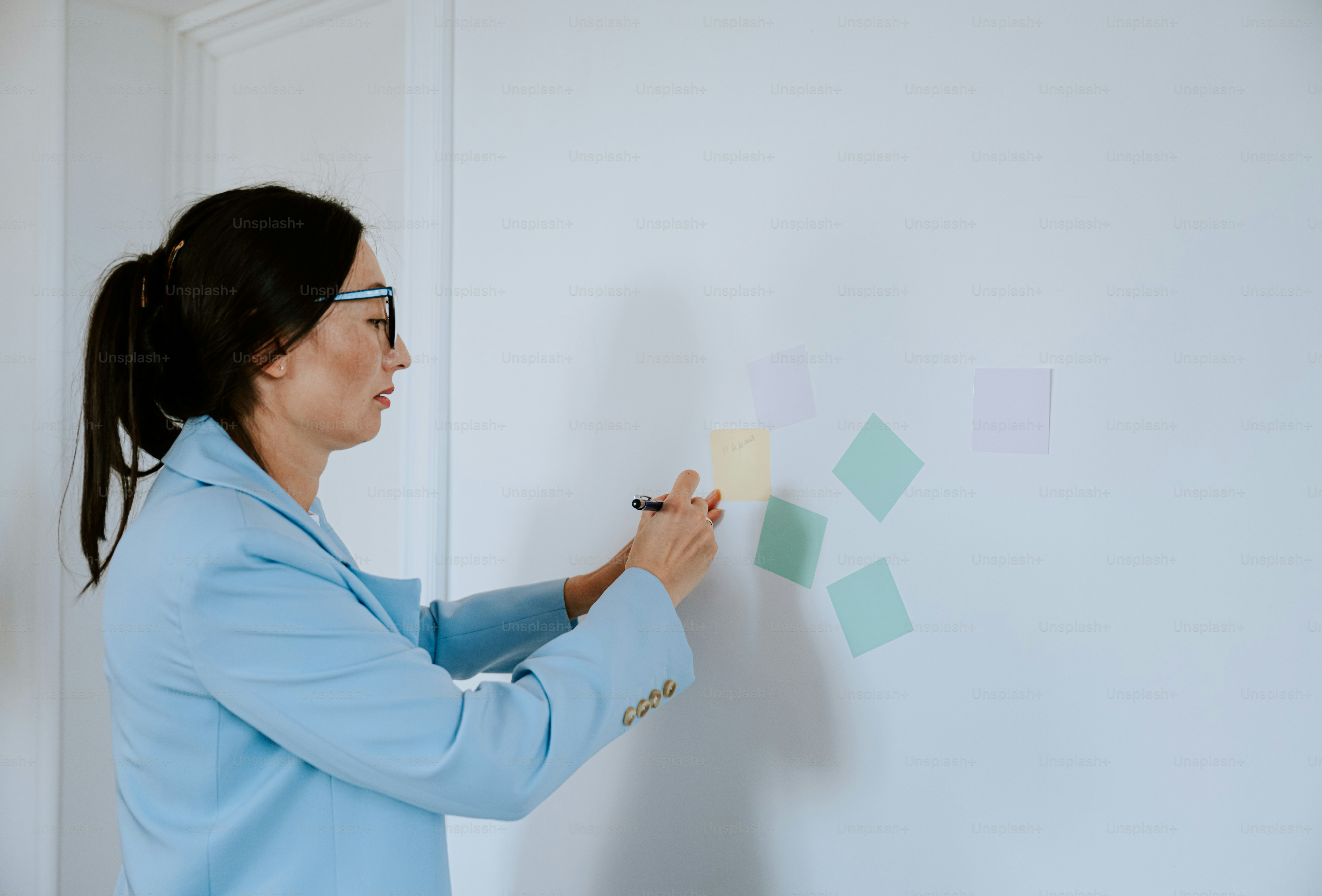 Woman in blue jacket writing on sticky notes photo – Writing Image on ...