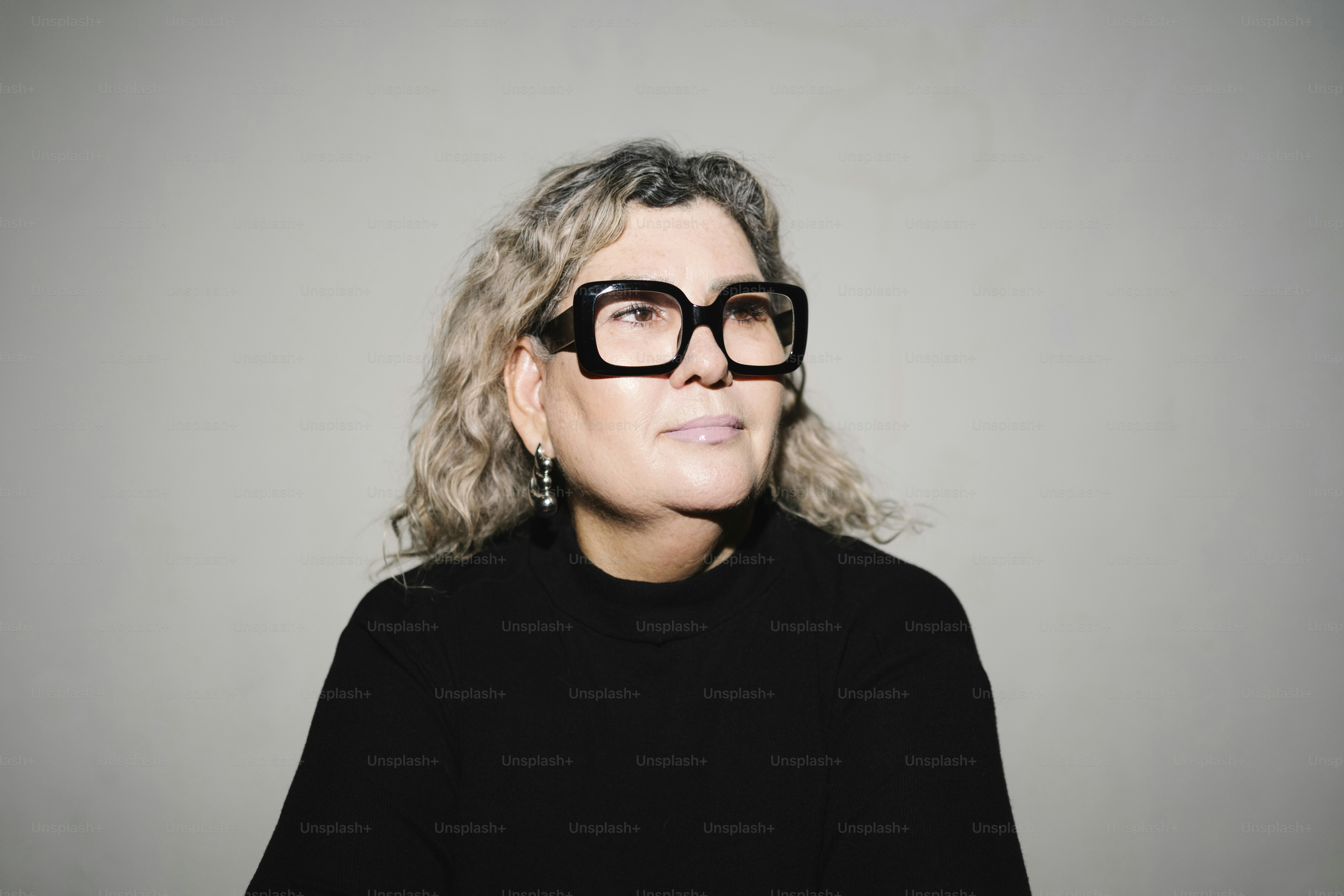 Woman with curly hair and glasses looking away