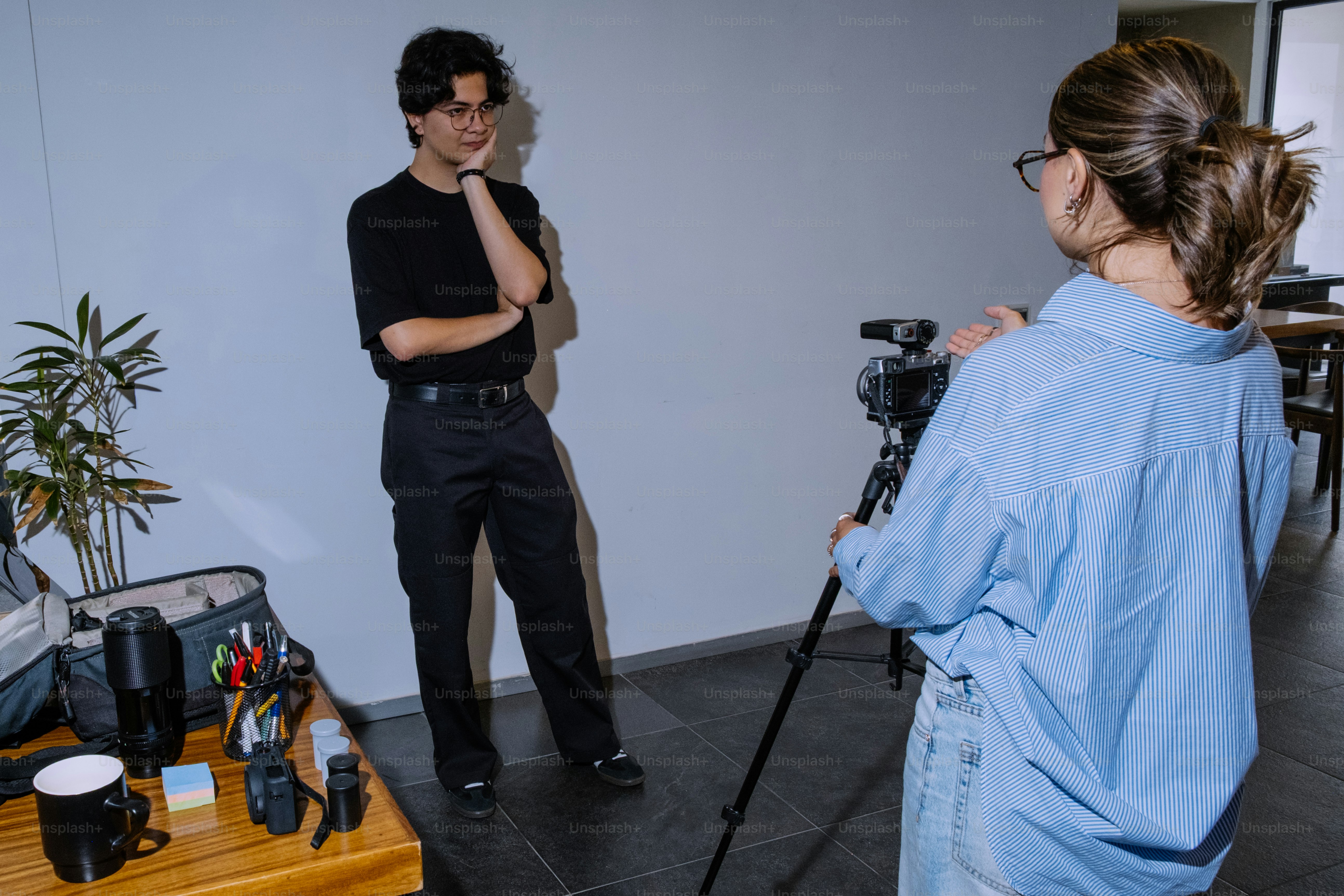 남자가 카메라를 향해 포즈를 취하고 여자가 그를 촬영하고 있습니다.