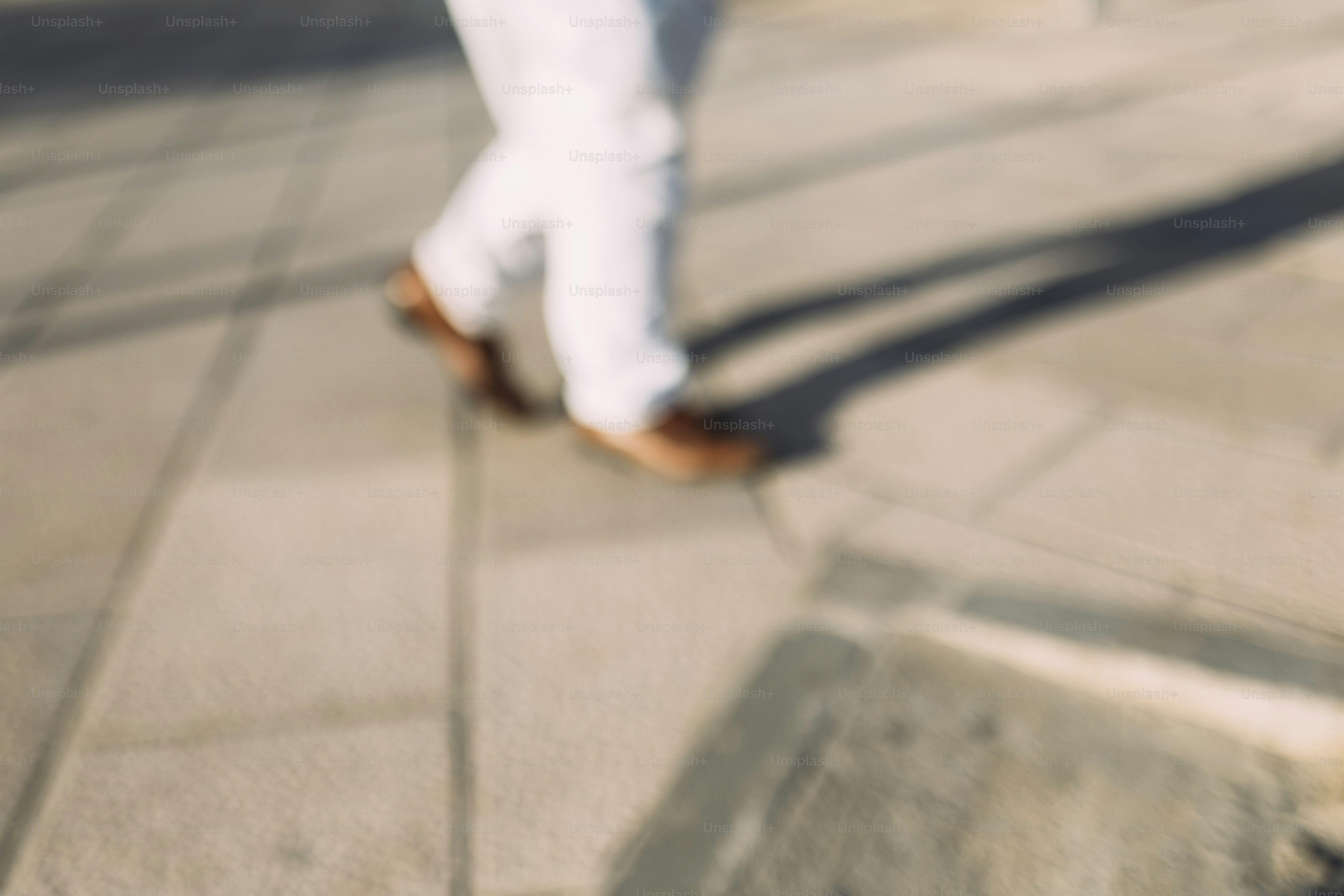 Person walking on a paved sidewalk casting shadows.