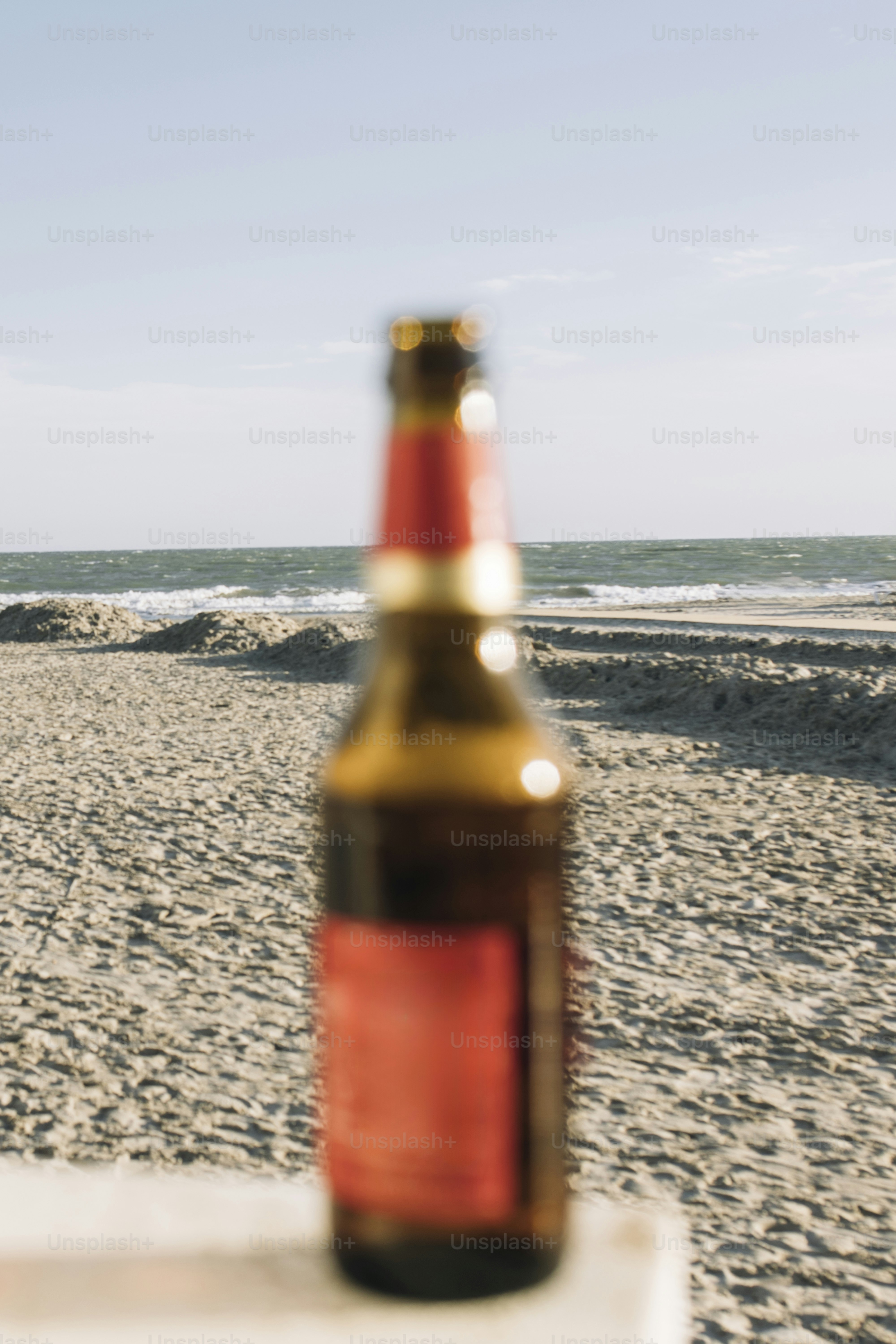 A bottle of beer on a sandy beach.