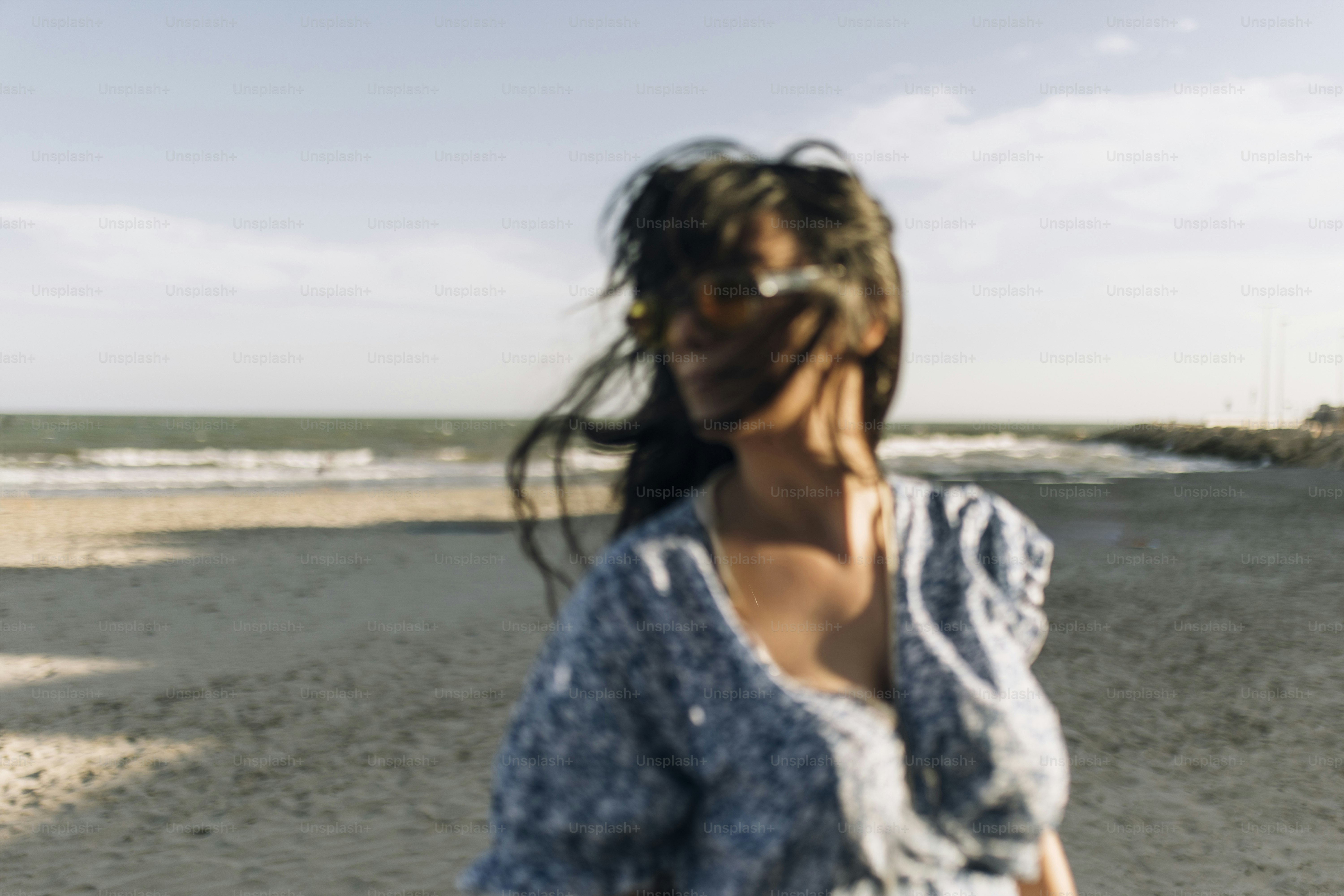 Woman with windblown hair on a sunny beach.