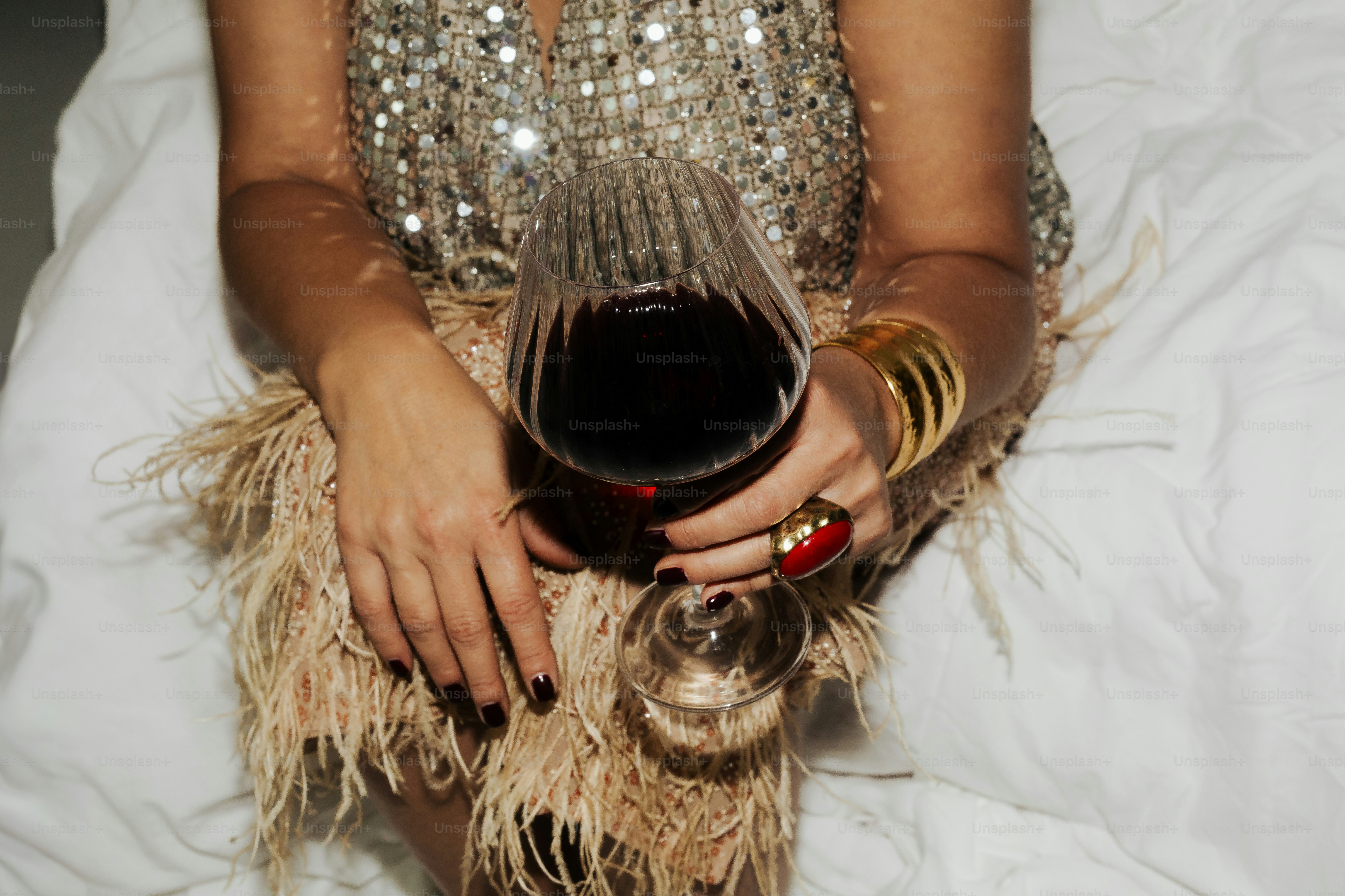 Frau in glitzerndem Kleid hält Rotweinglas