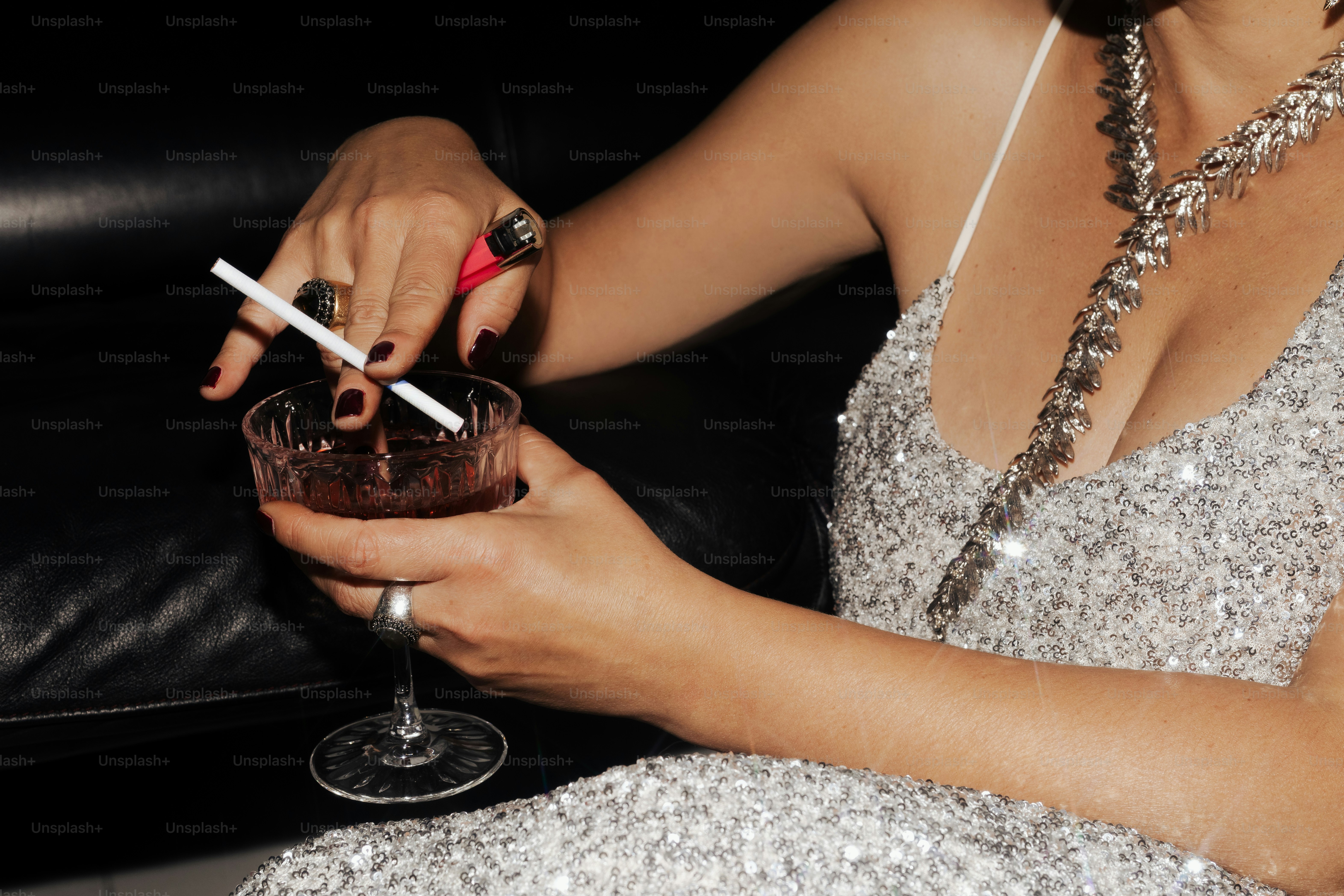 Woman in sequined dress holding cocktail and stirring cocktail
