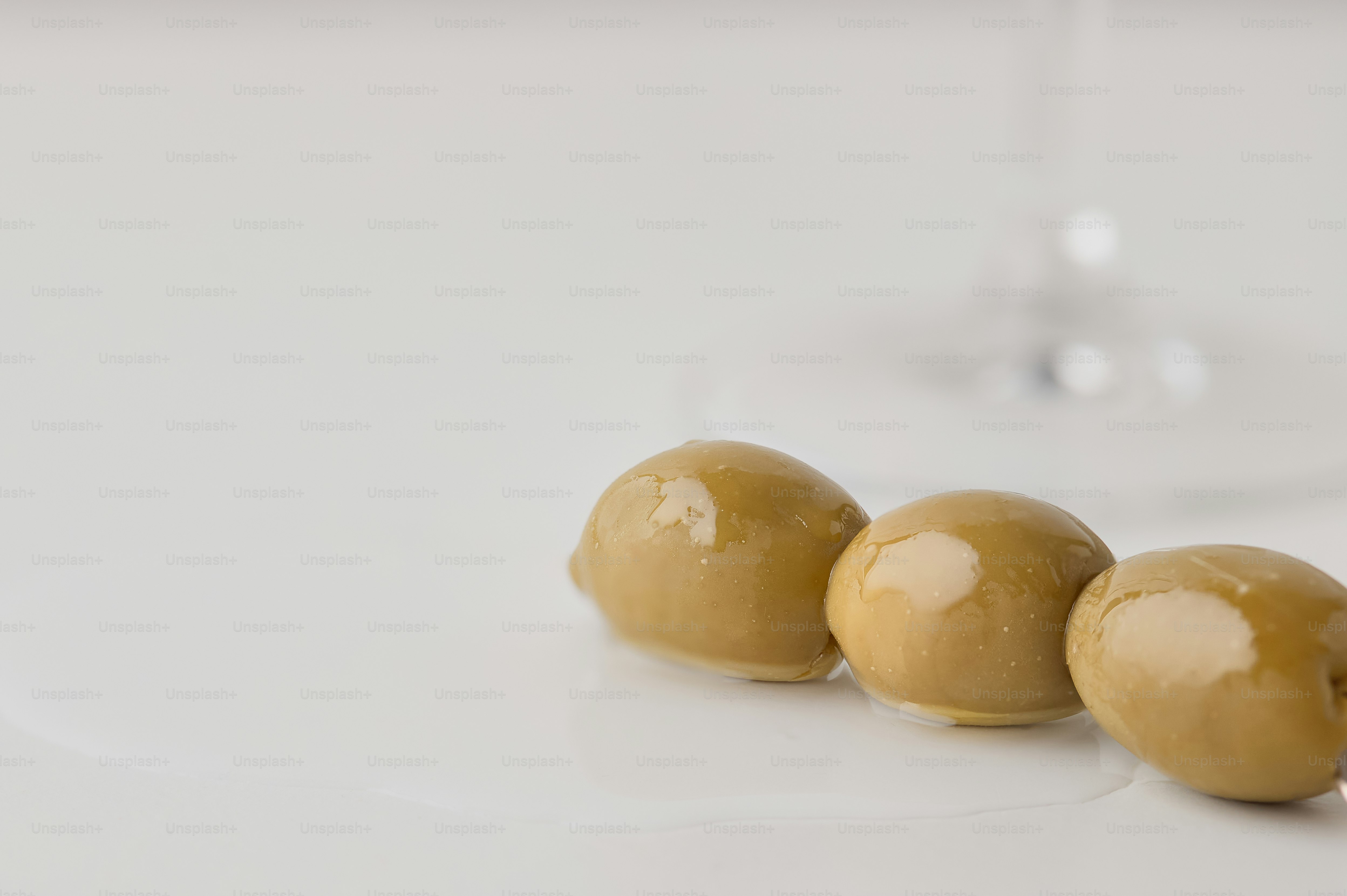 Three green olives on a white surface